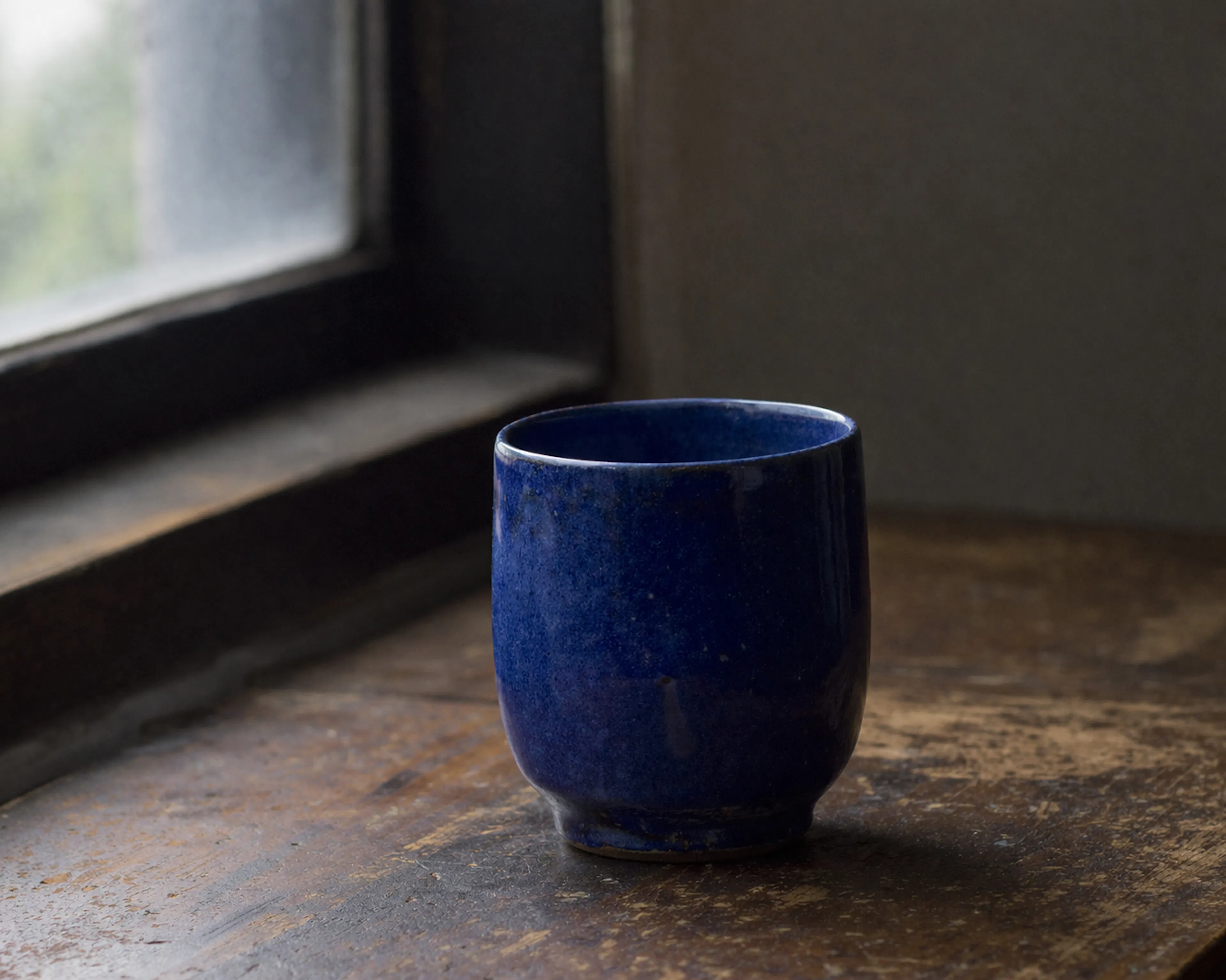 A single handmade ceramic cup in deep cobalt blue