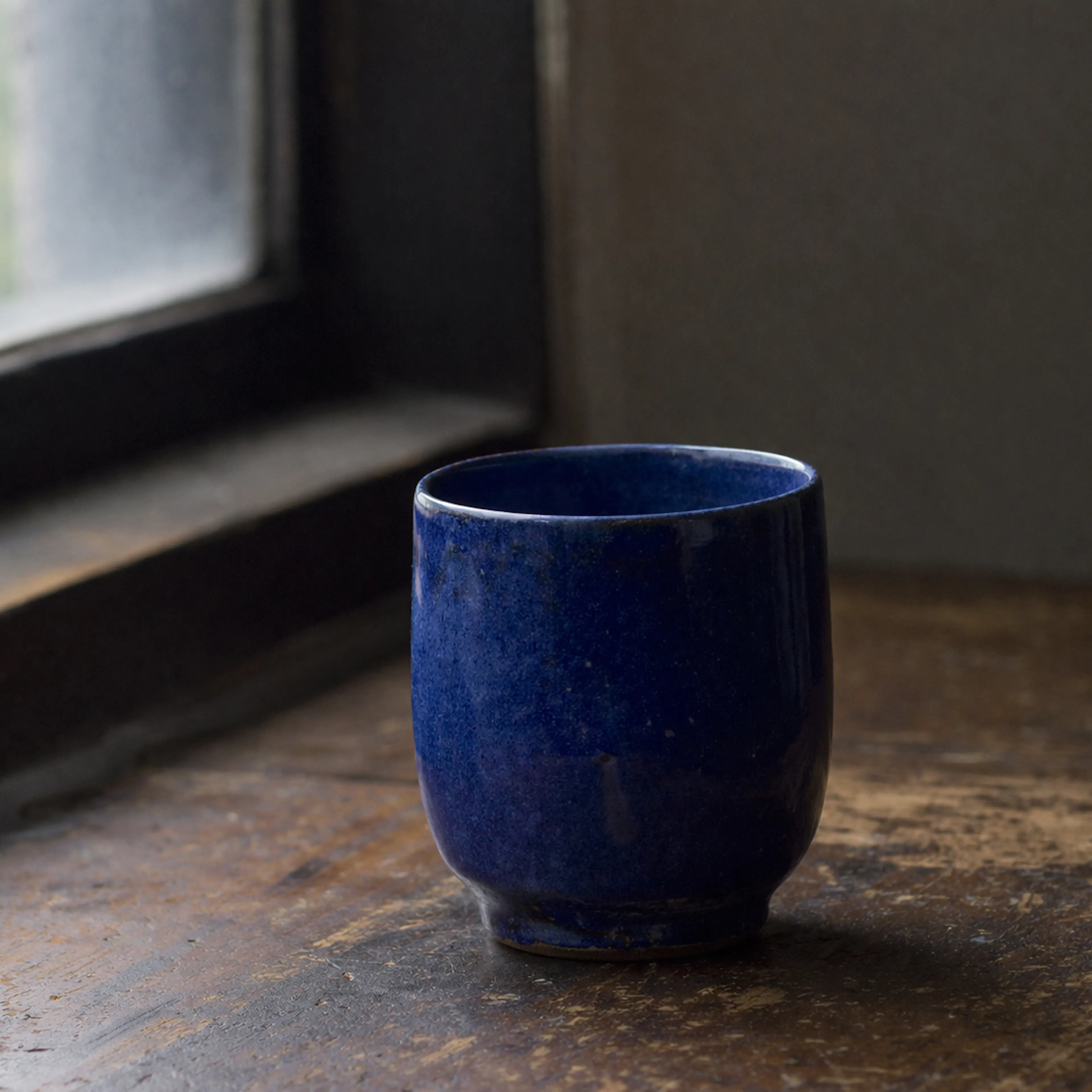 A single handmade ceramic cup in deep cobalt blue