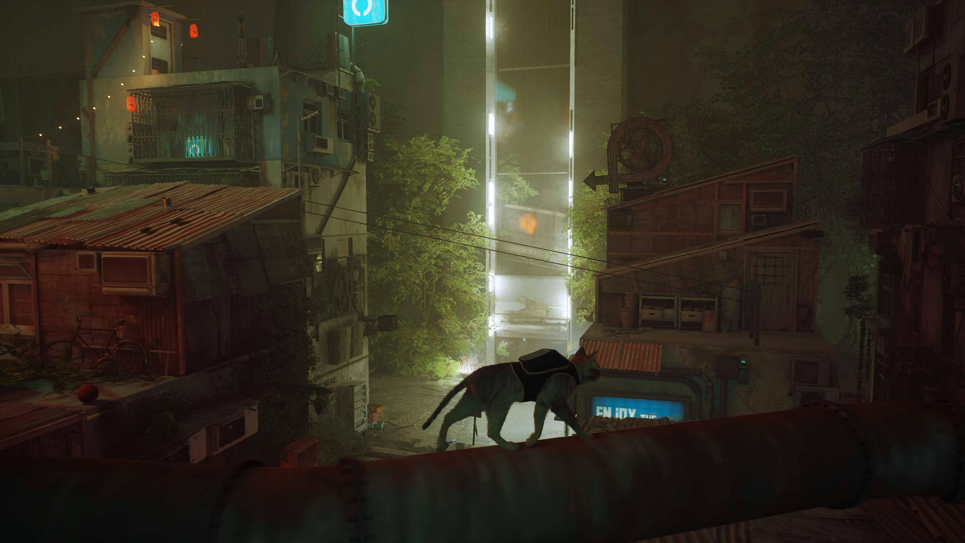 Foreground is shadowy. There's the silhouette of a cat walking across a pipe. In the background are piles of boxes, screens, and some buildings. You can also see bright white lights in background, and a string of red lantern lights off to the left.