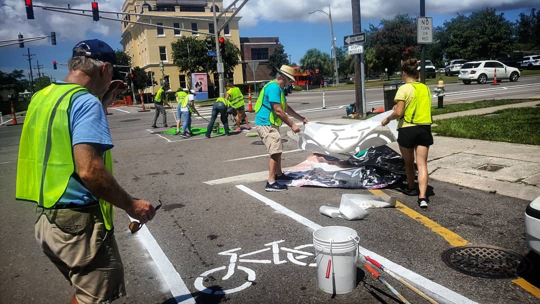 Volunteers paint “sharrows” onto a street in New Orleans to help mark bike routes. (Source: Bike Easy.)