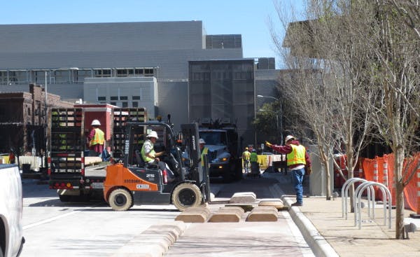 Workers assemble modular curbs for a protected bike lane on 3rd Street in Austin