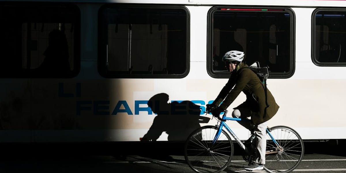 Woman biking in front of a bus, Credit: Colin Czerwinski/Unsplash