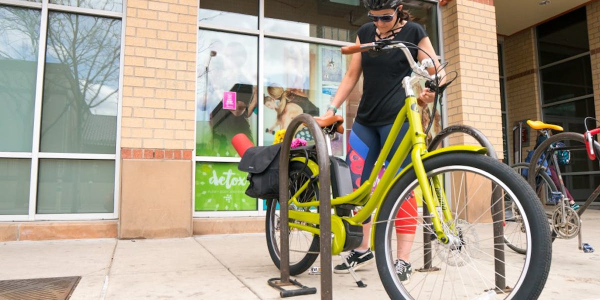 Woman adjusting her bike in front of a retail shop