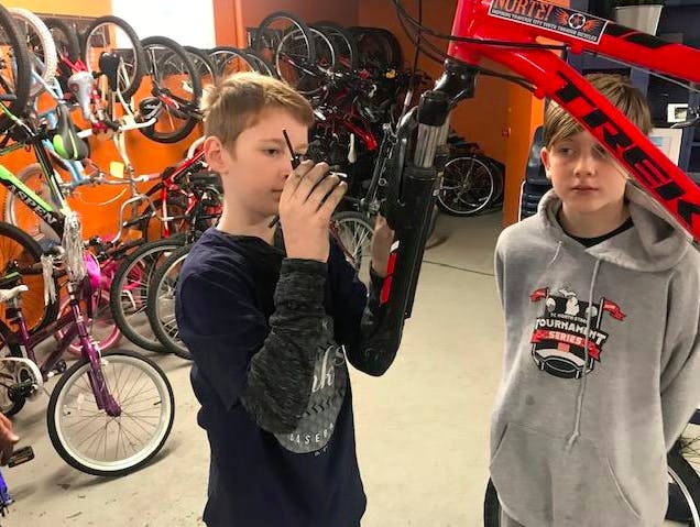 Kids learning how to fix a bike. Credit, Norte.
