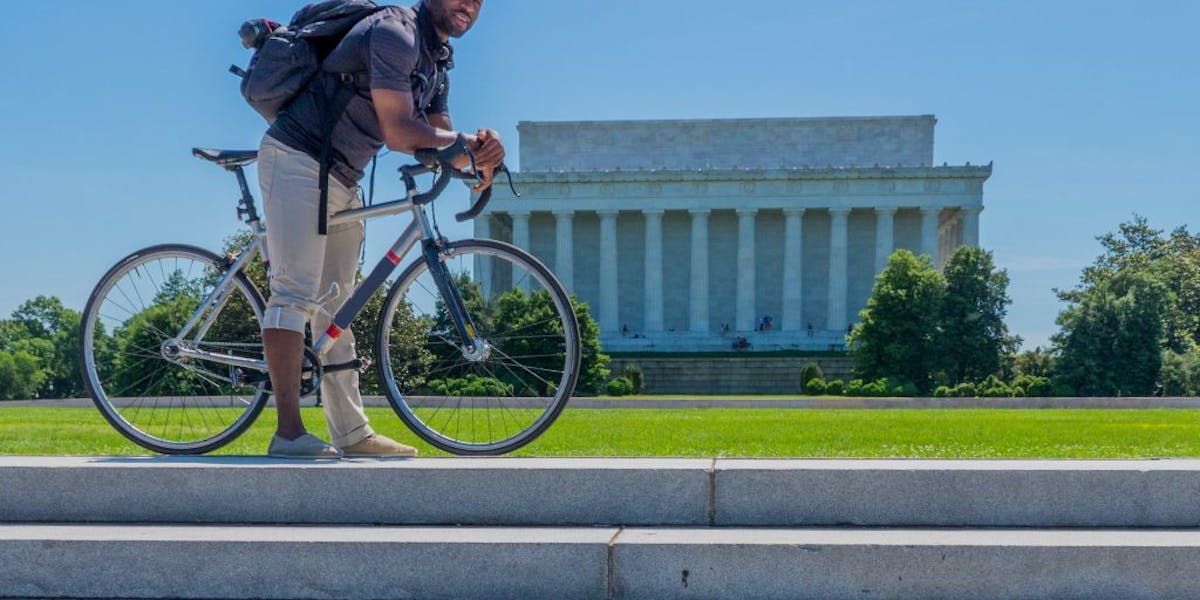 Man standing over his bicycle in front of the Lincoln Memorial
