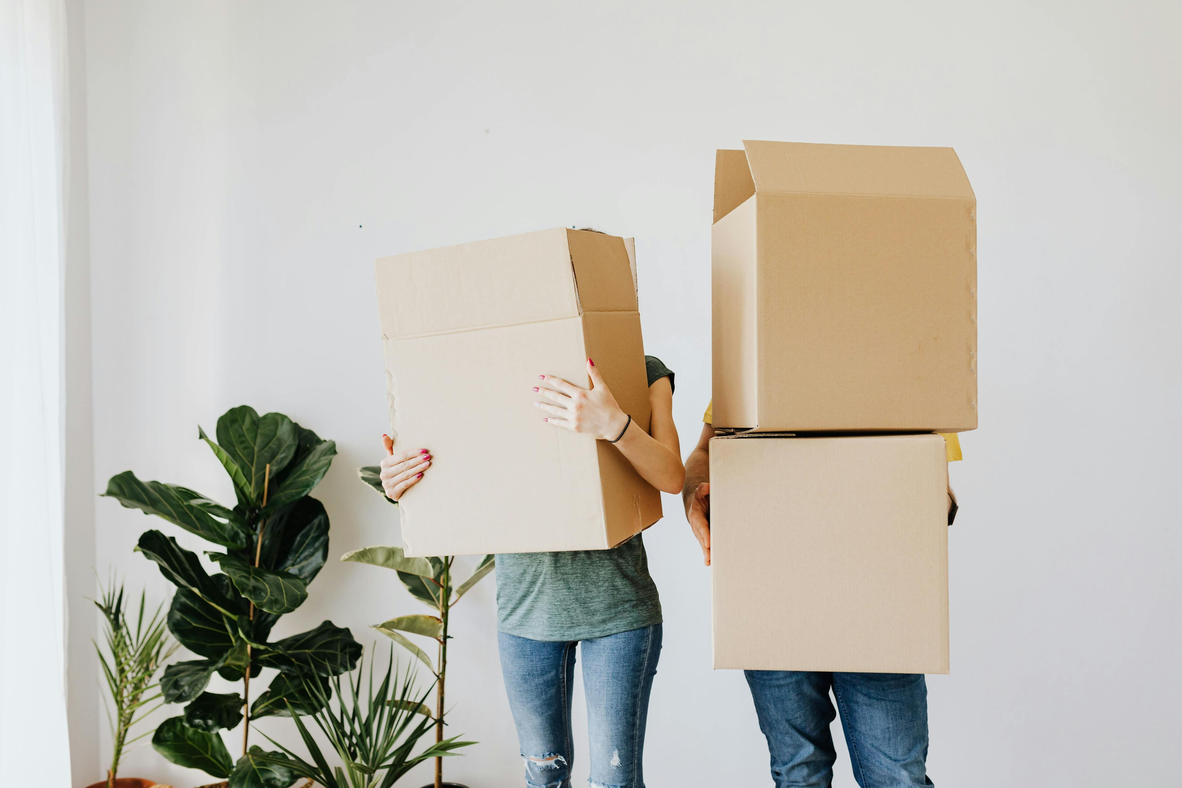 Two people in an apartment holding moving boxes