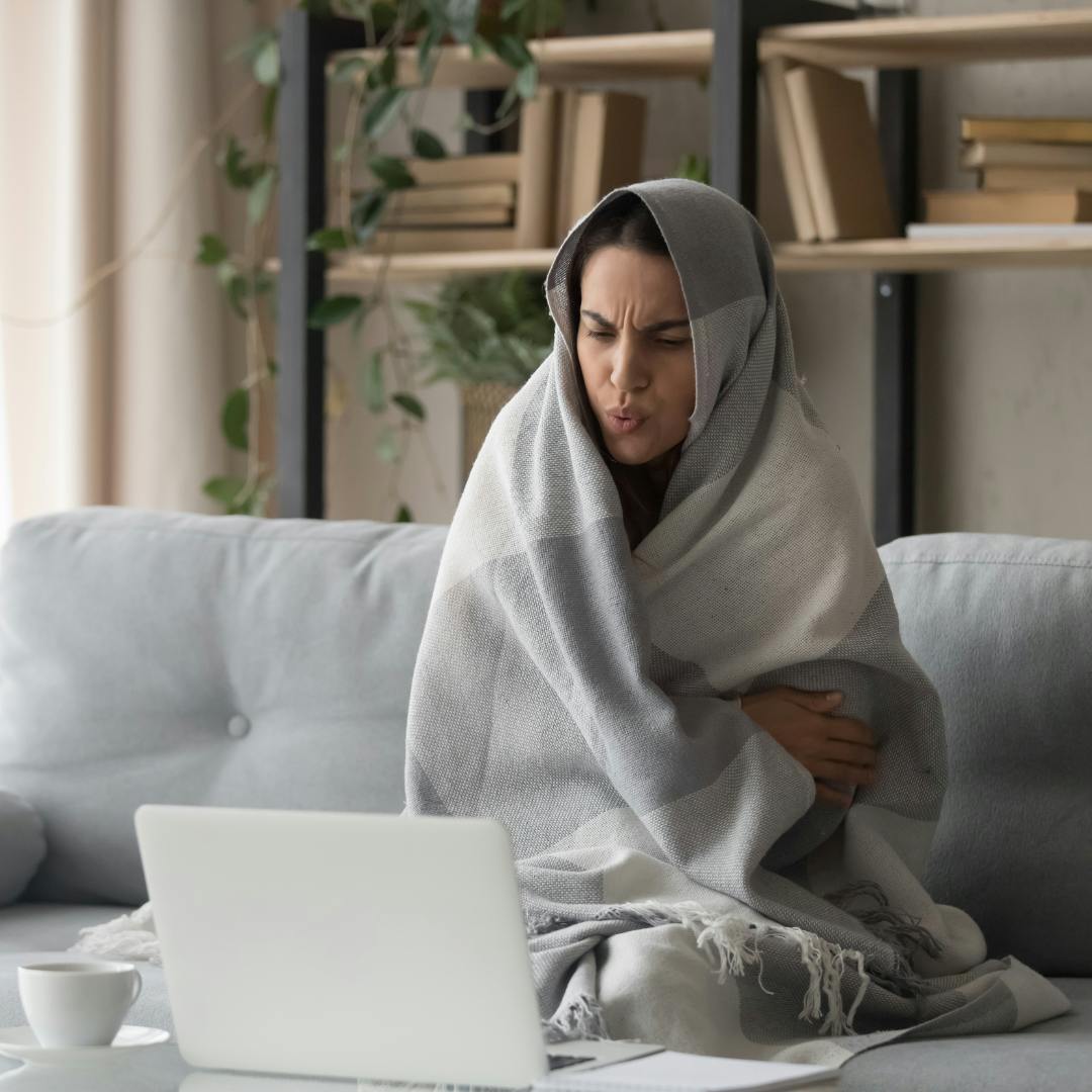 Cozy woman wrapped in a blanket staying warm in a cold apartment, illustrating energy-efficient living during the winter.