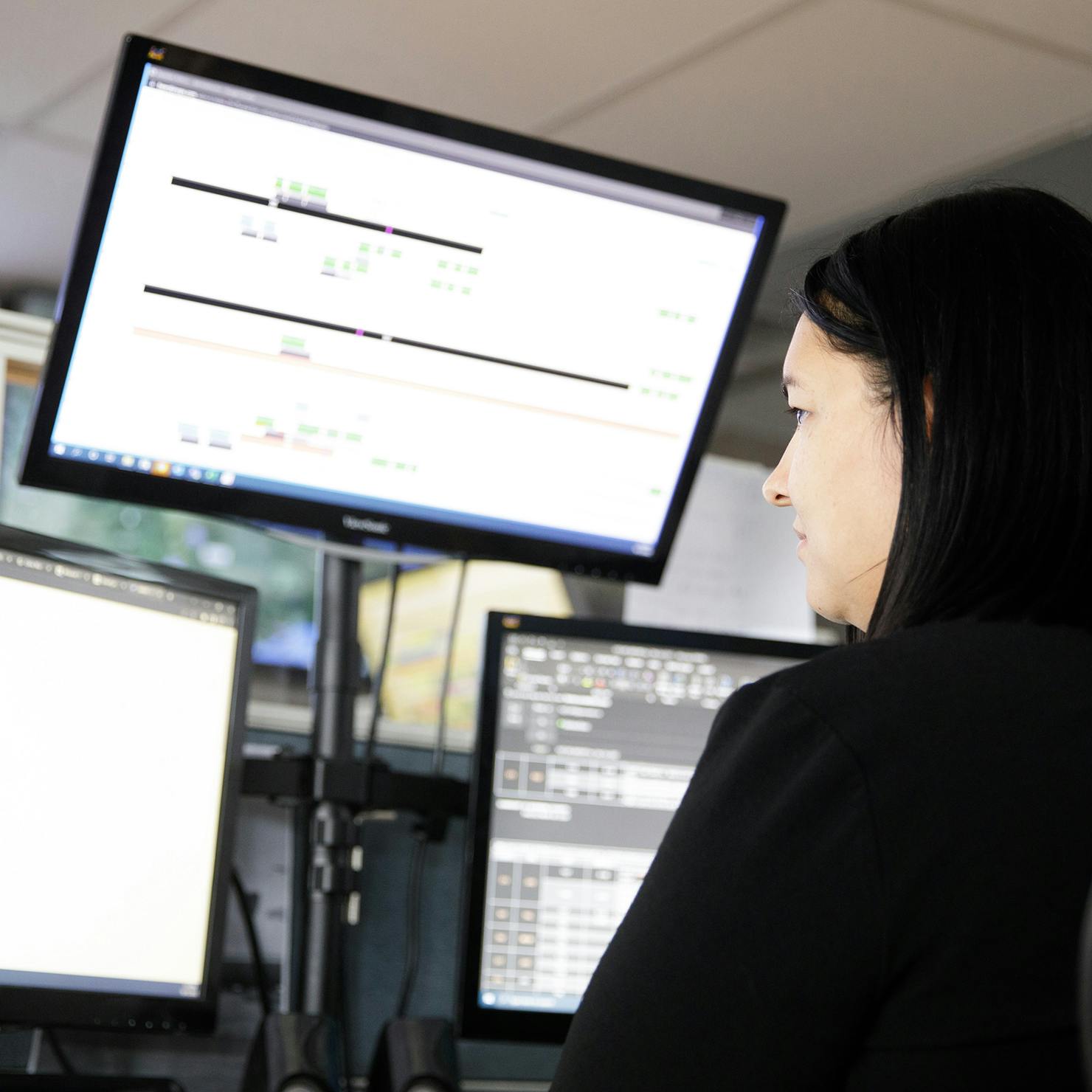 Woman looking at flight boards on computer screens in flight operations.