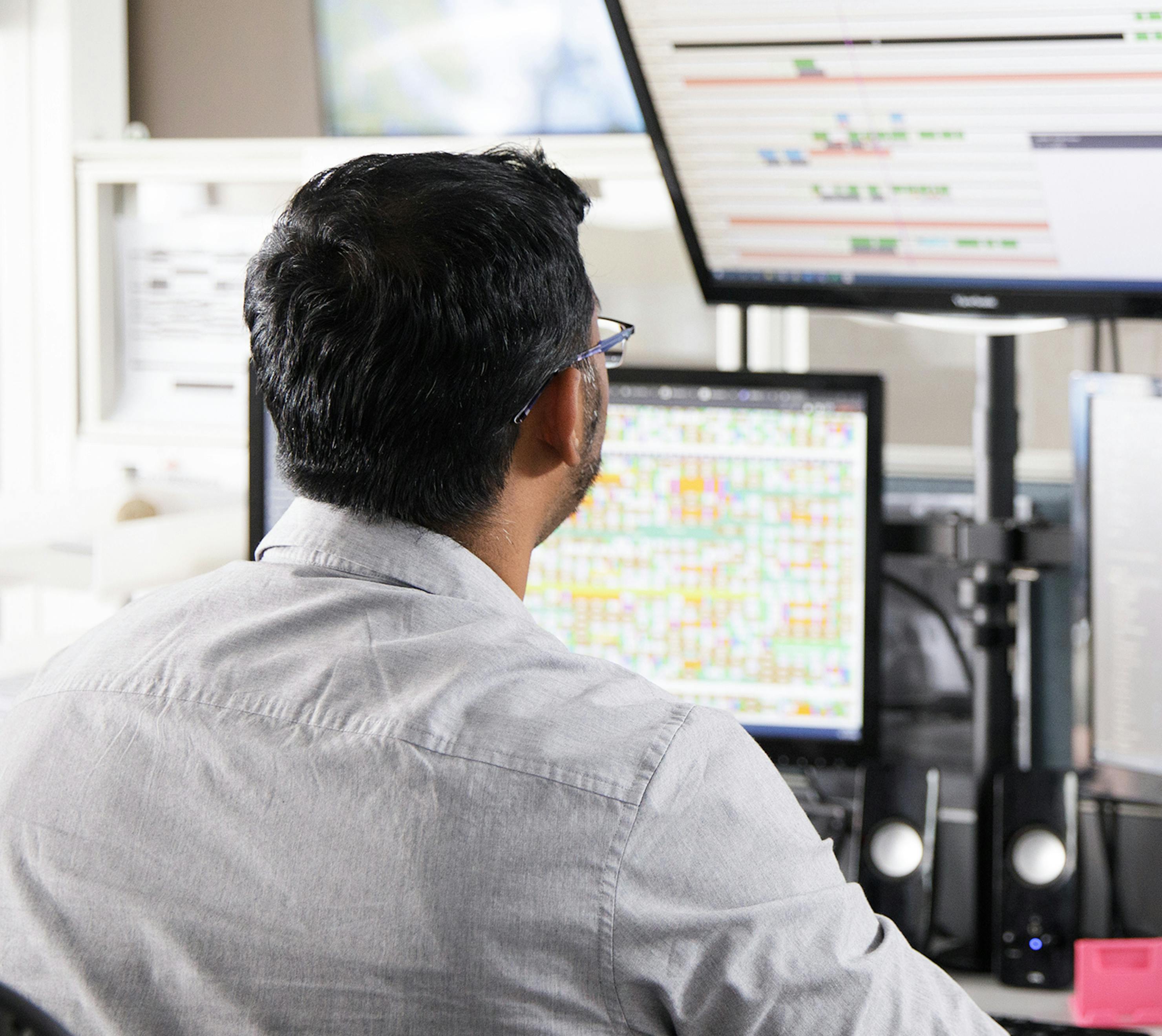 Man looking at flight boards on two computer screens in flight operations.