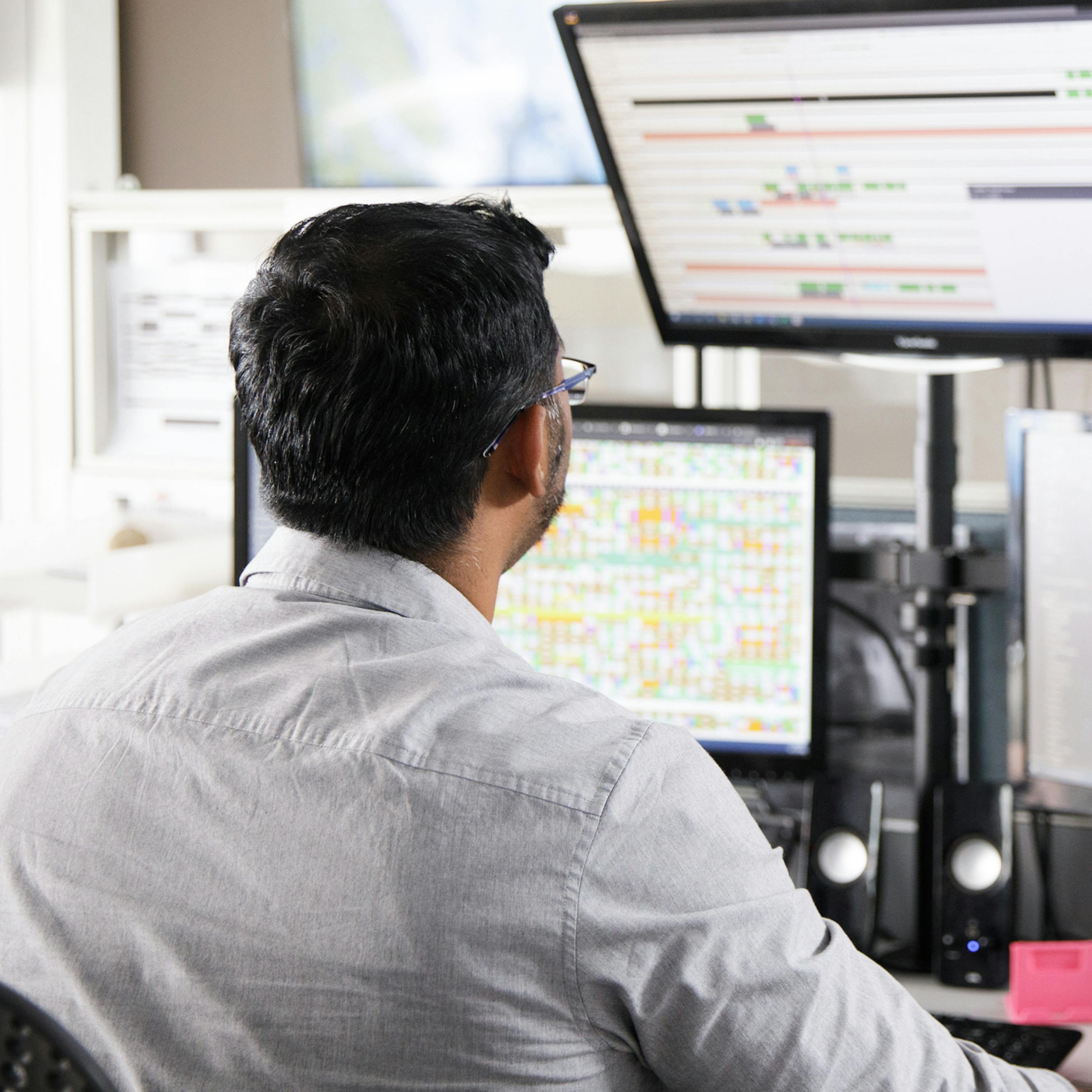 Man looking at flight boards on two computer screens in flight operations.