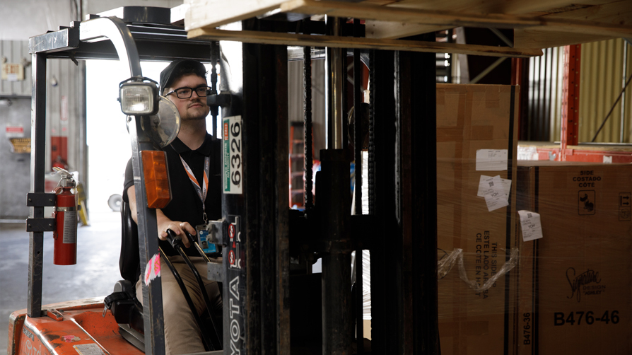 Man using forklift in cargo warehouse.