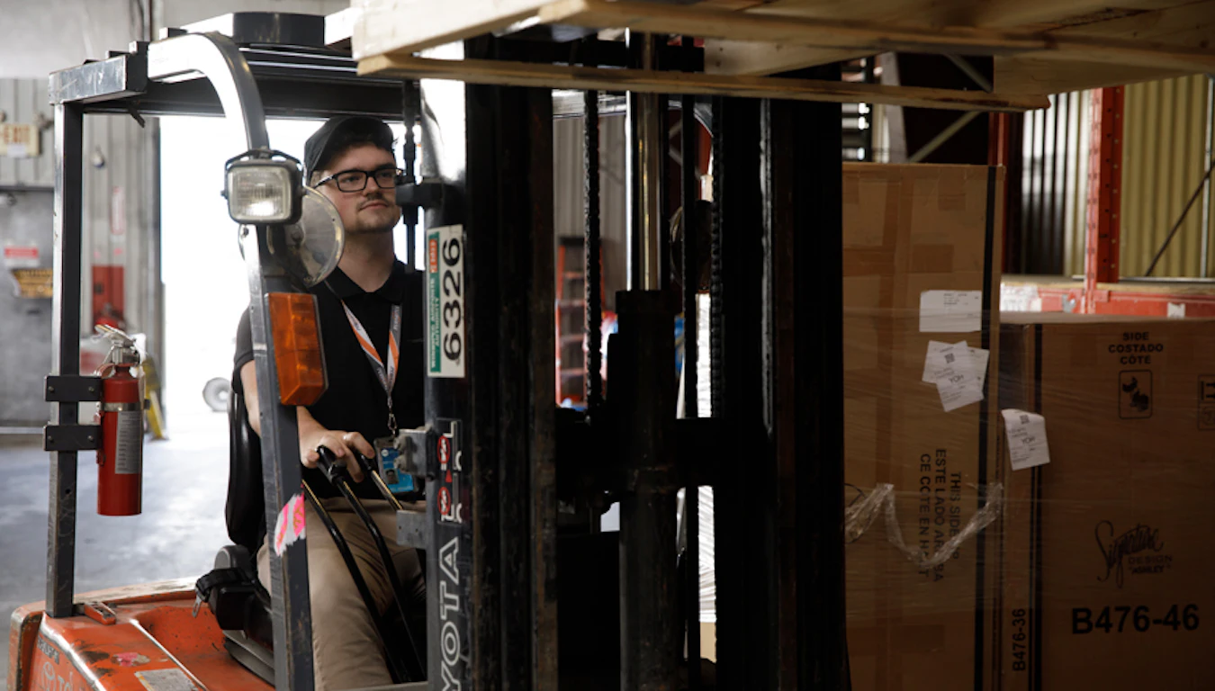 Man using forklift in cargo warehouse.