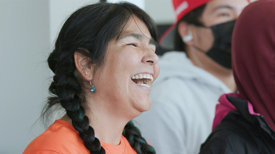 Woman in an orange shirt smiling.