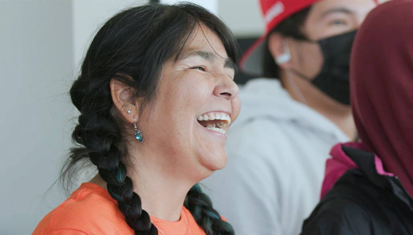 Woman in an orange shirt smiling.