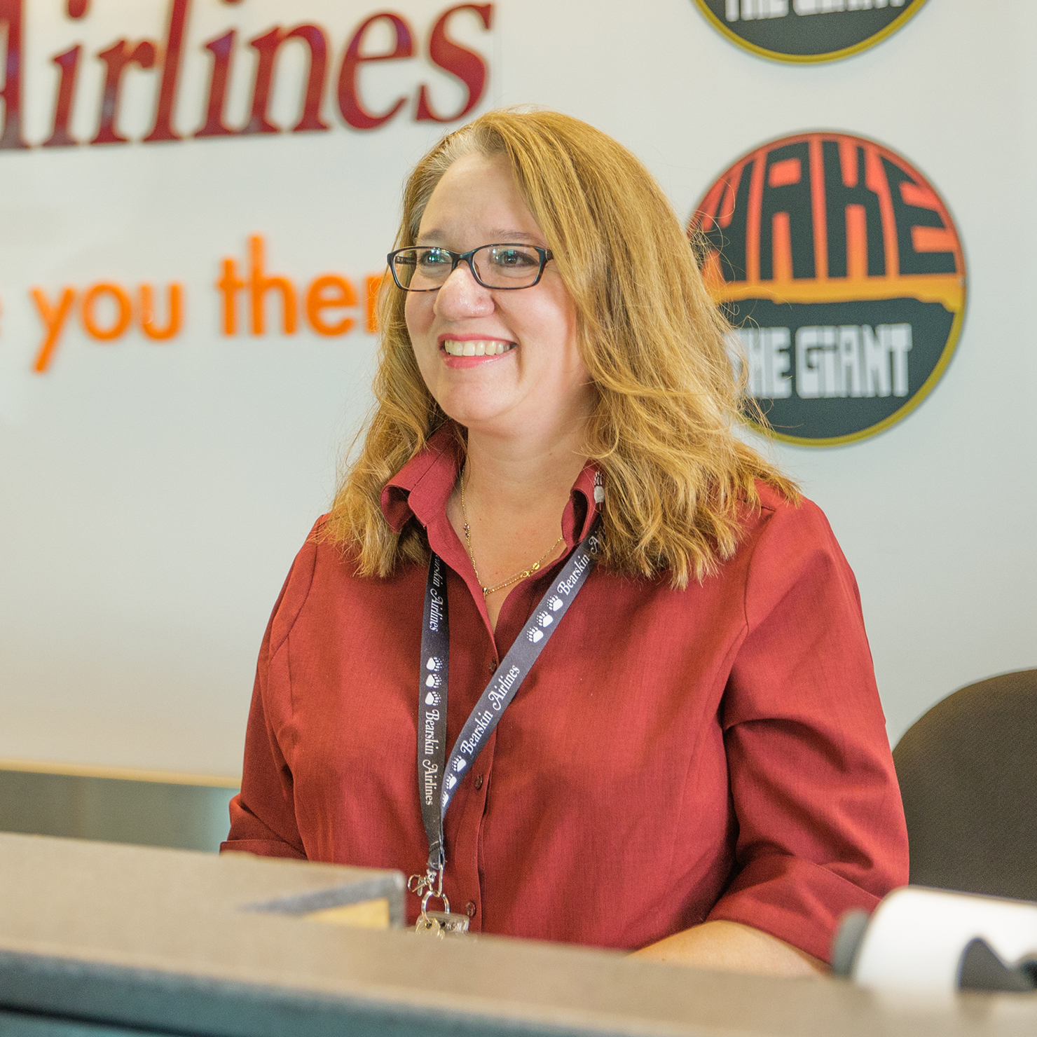 Woman at check-in counter smiling off camera.