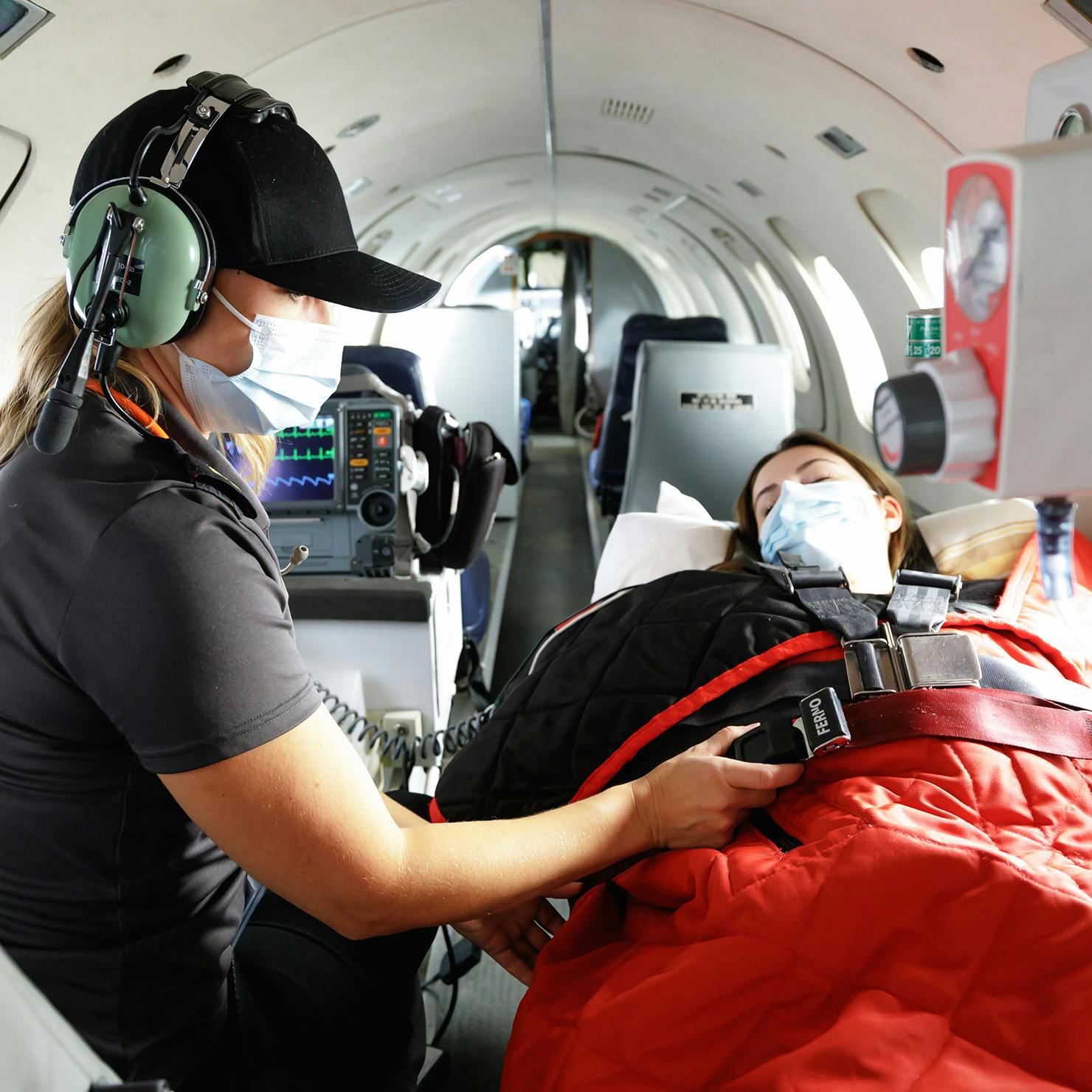 Medevac nurse securing patient inside airplane for take off.