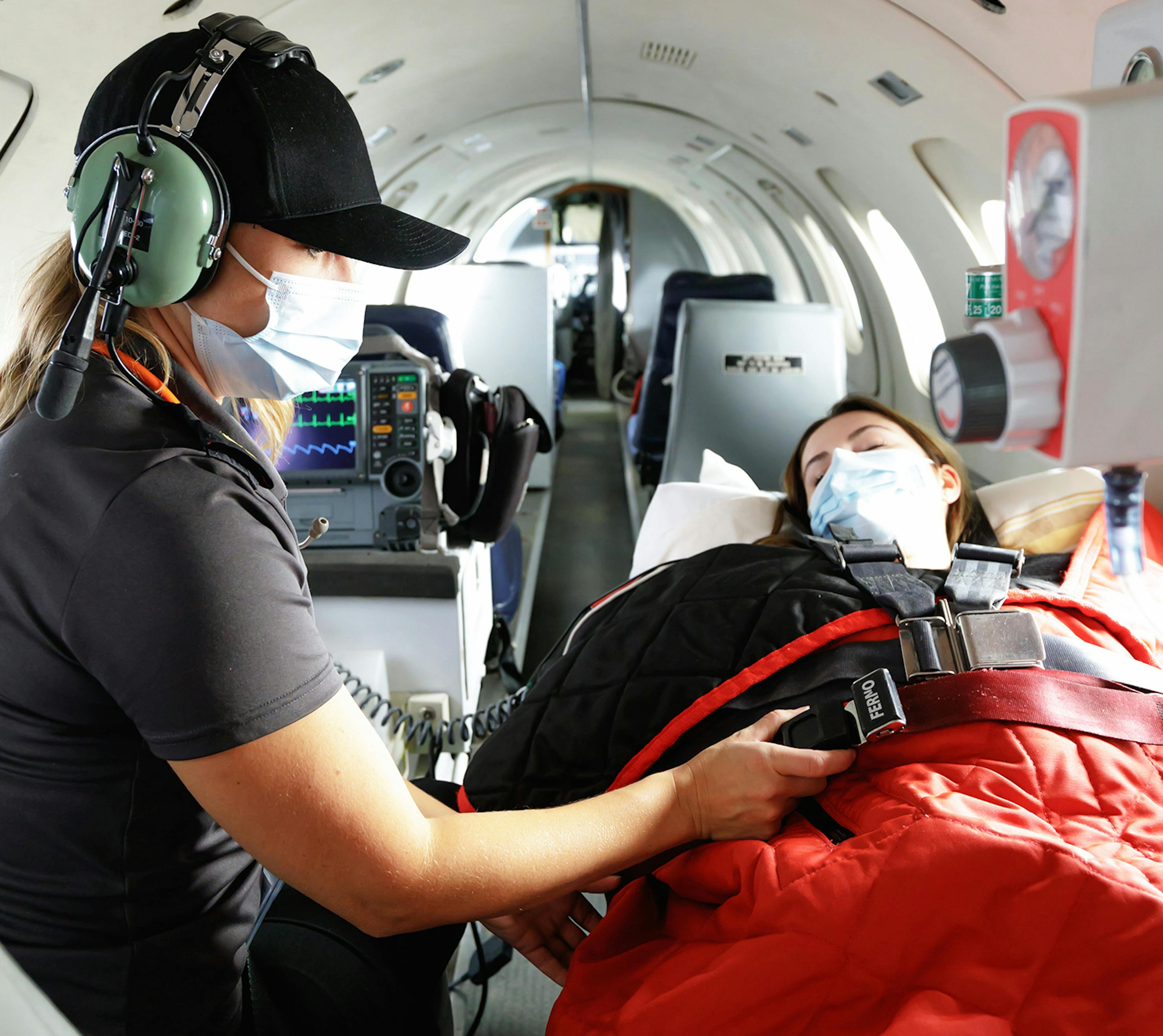 Medevac nurse securing patient inside airplane for take off.