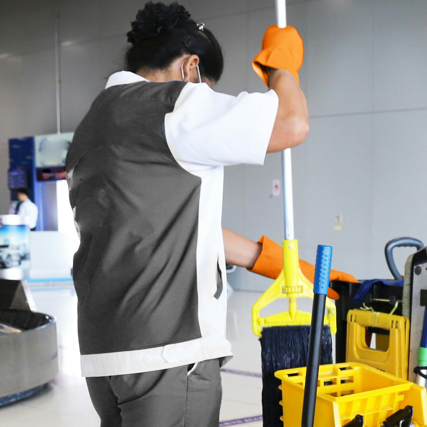 Airport cleaner lifting mop out of bucket.