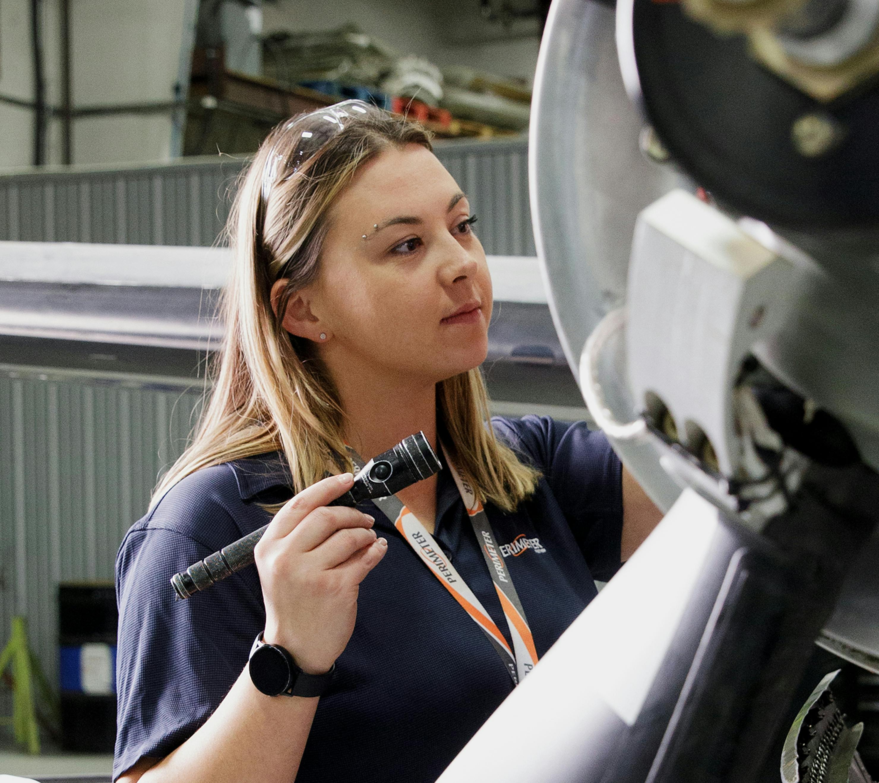 Woman inspecting airplane engine.