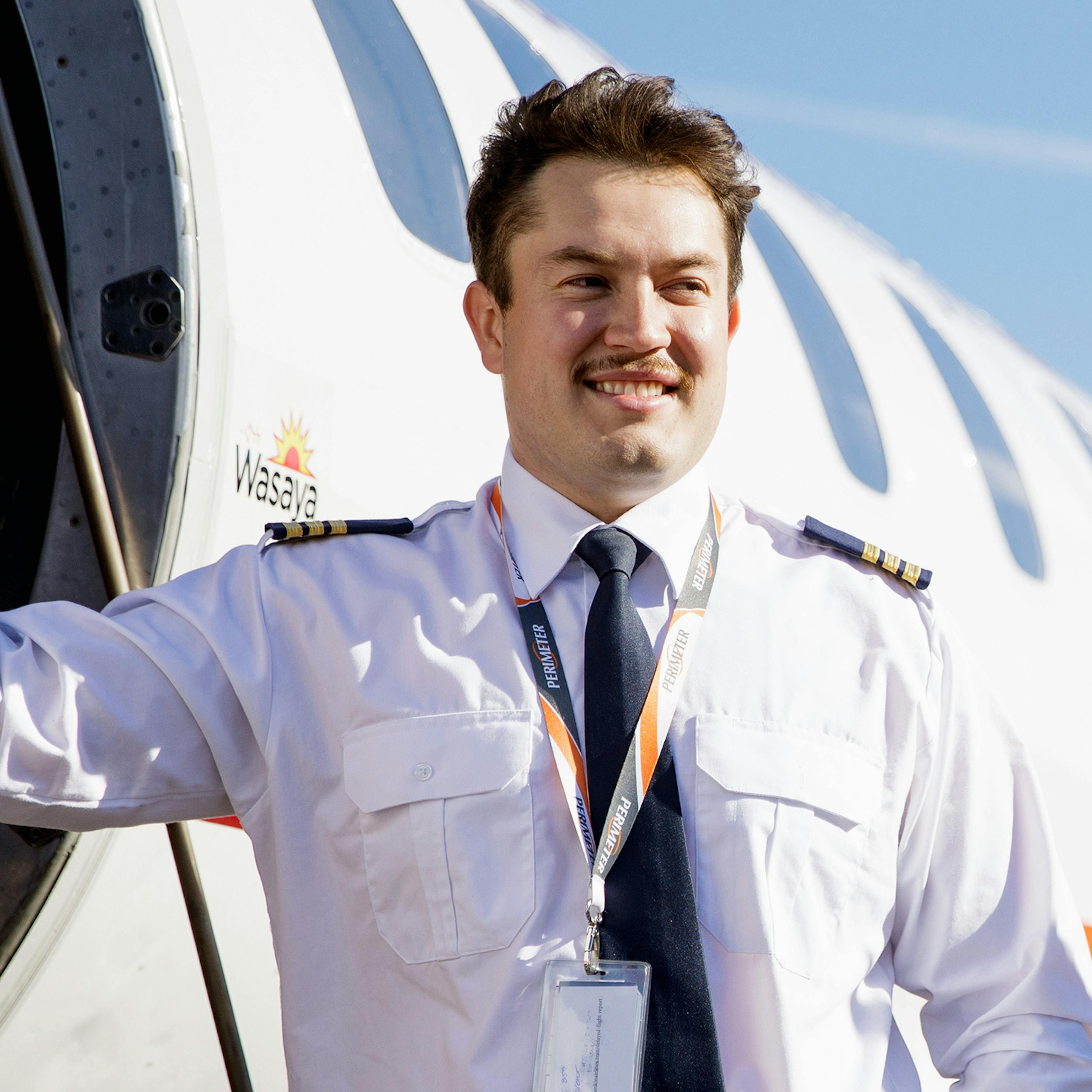 Pilot smiling and leaning again the aircraft entrance.