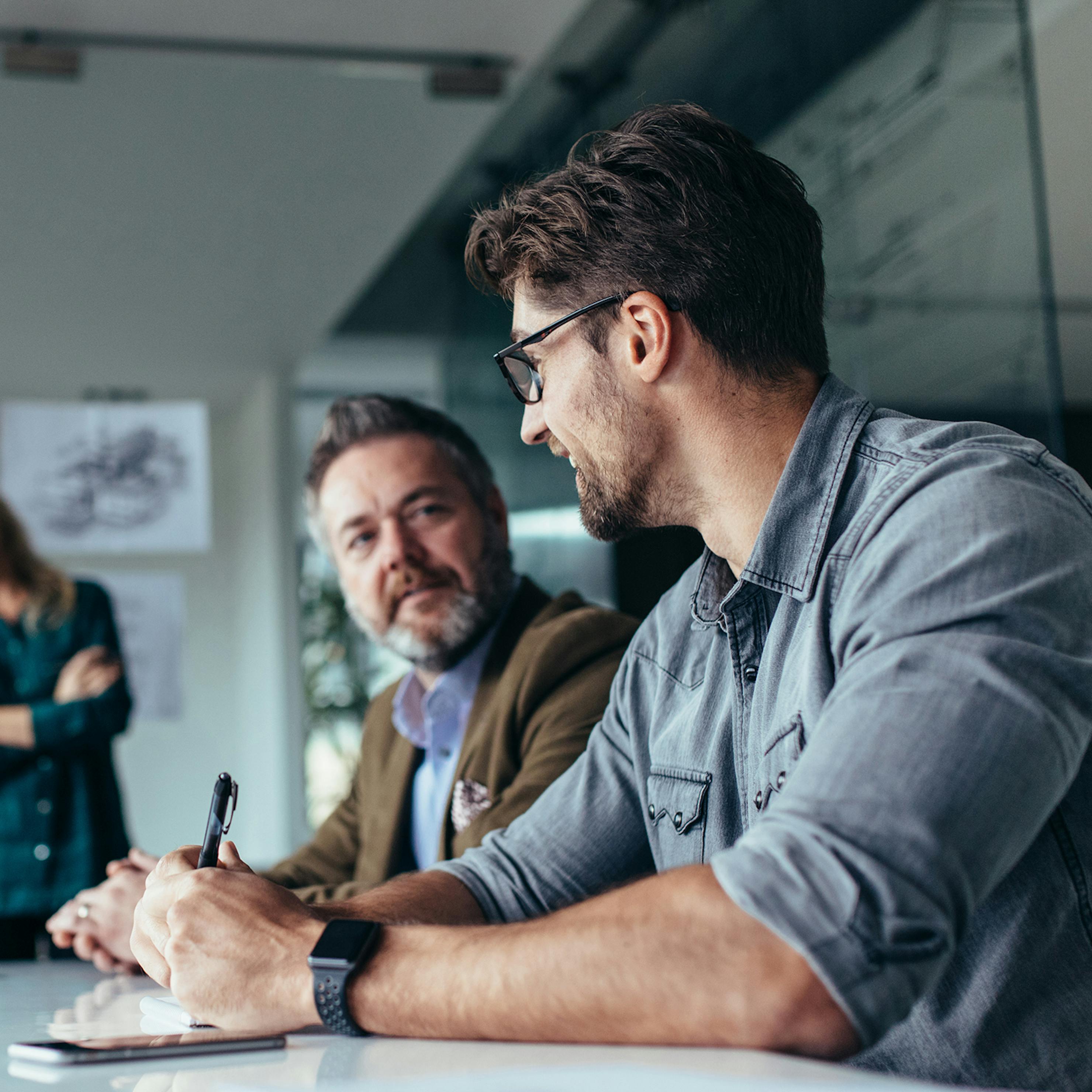 Two men in boardroom laughing and chatting.