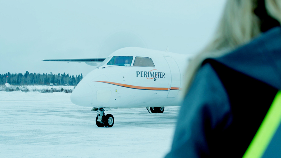 Perimeter Aviation aircraft over the shoulder of a woman.