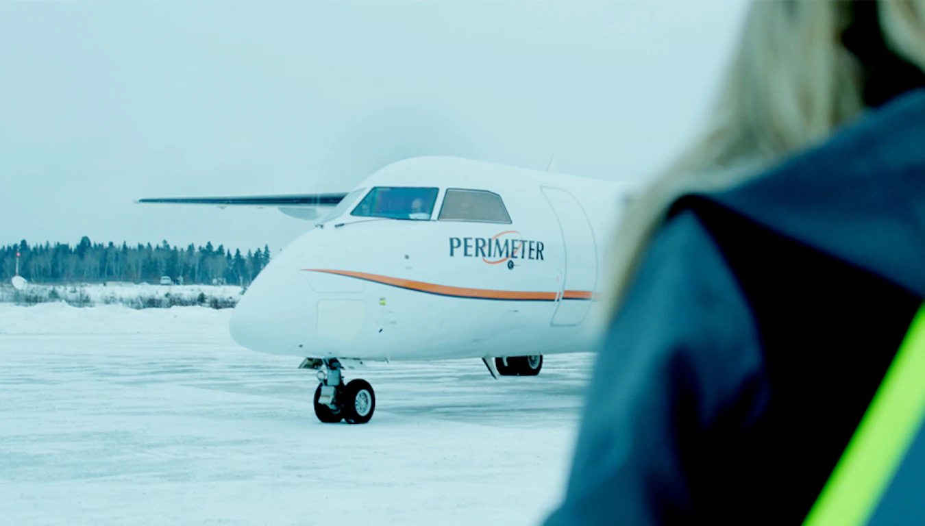 Perimeter Aviation aircraft over the shoulder of a woman.