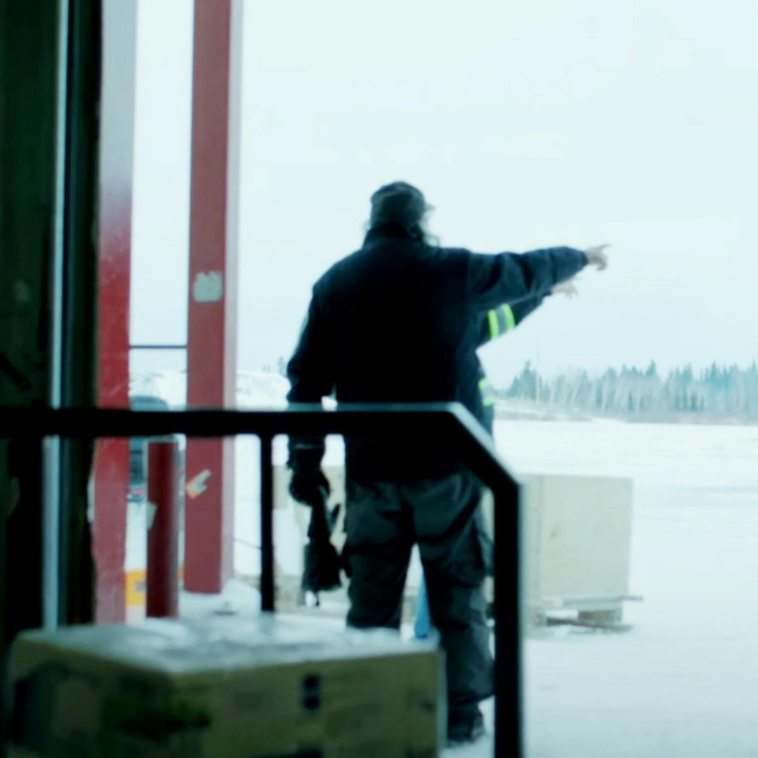 Two men at the entrance of the cargo room pointing into the distance at a Northern Station.