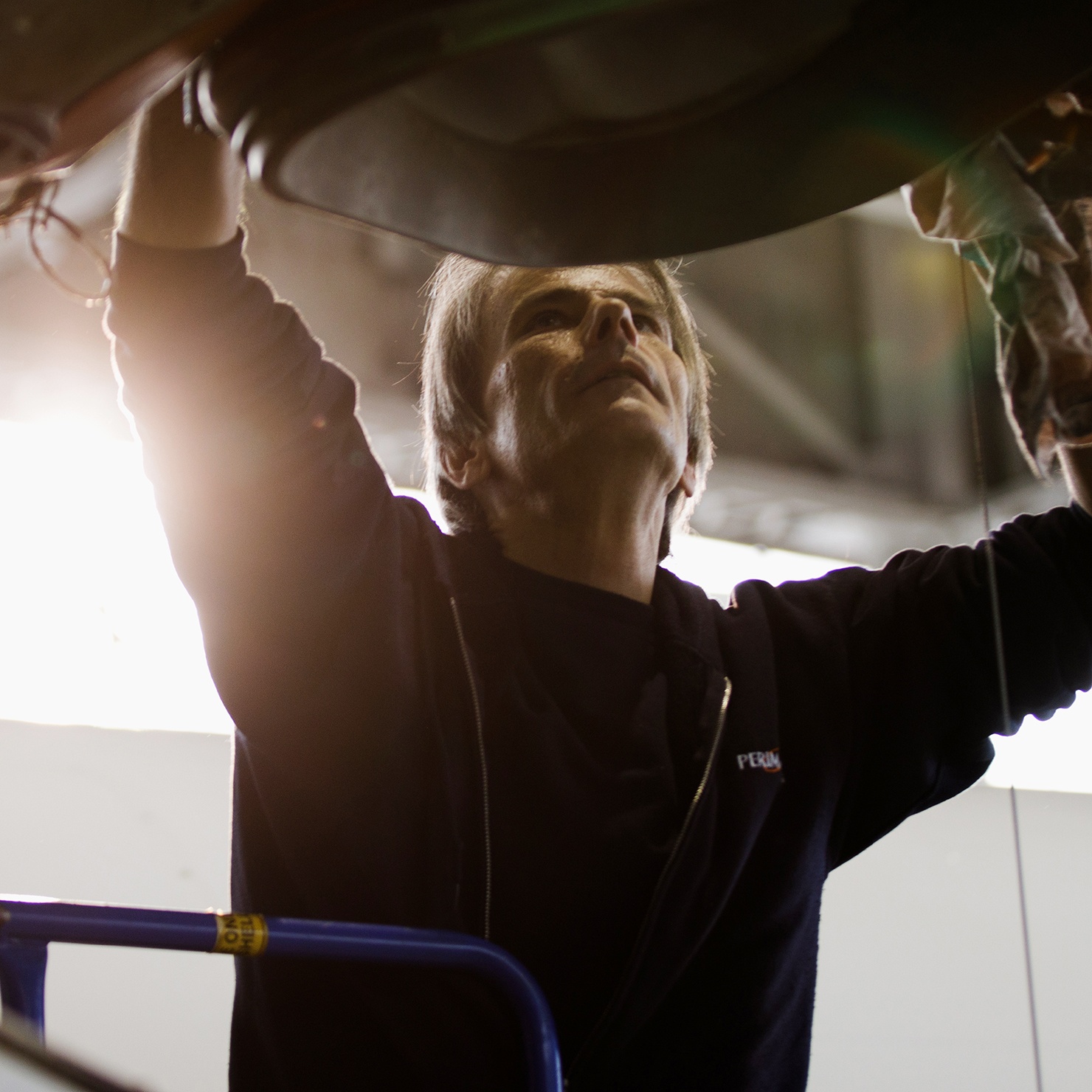Aircraft Maintenance Engineer looking above his head to work on an aircraft engine.