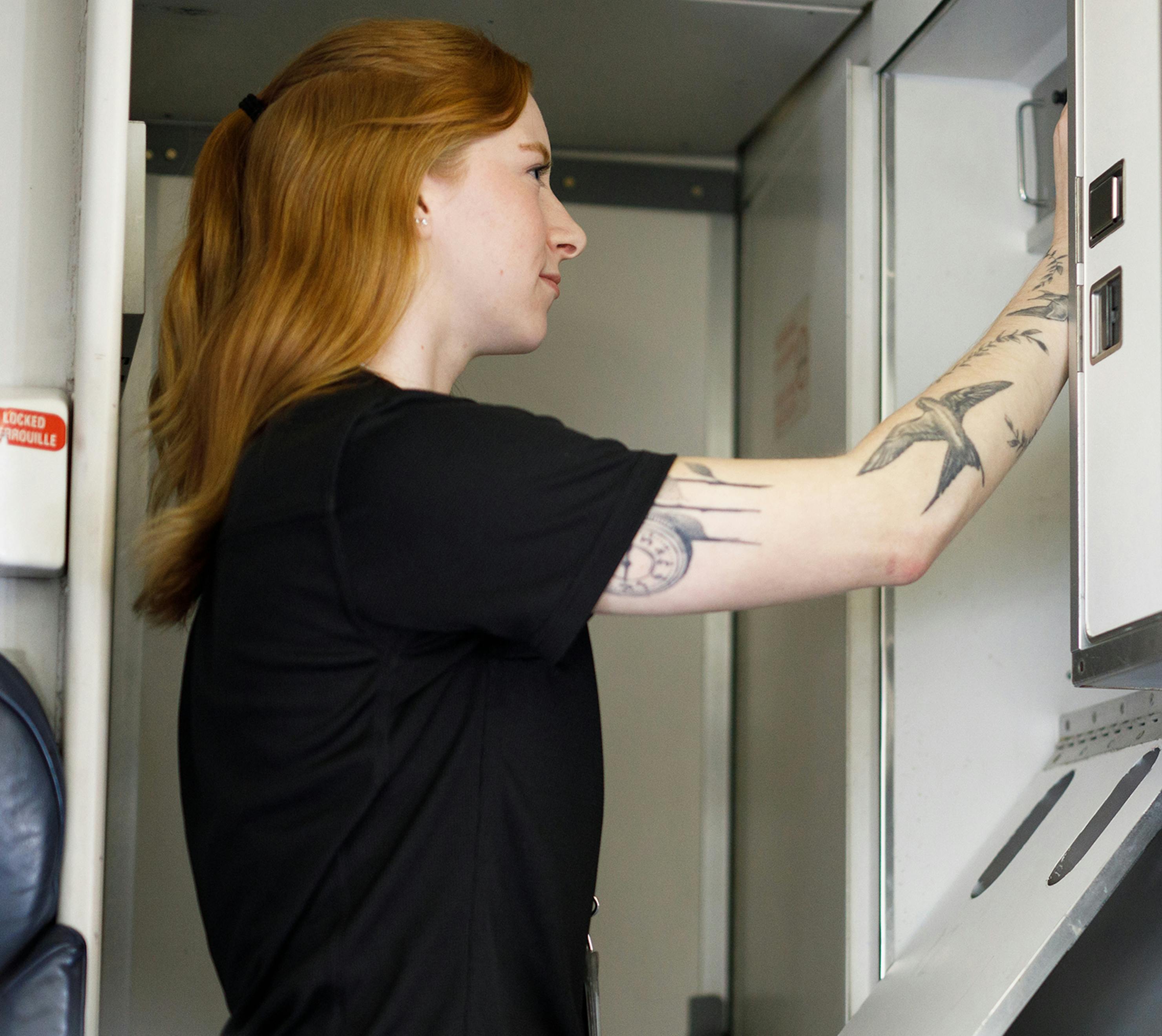 Flight attendant on aircraft by cockpit, opening door to access commissary.