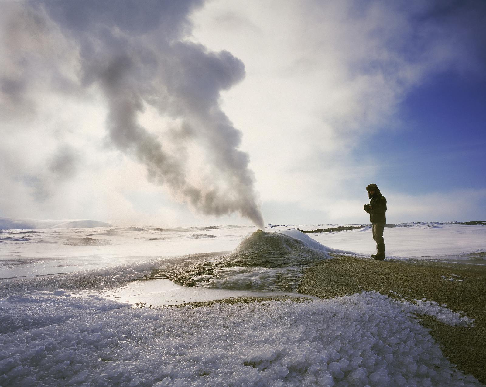man standing by a geyser during winter
