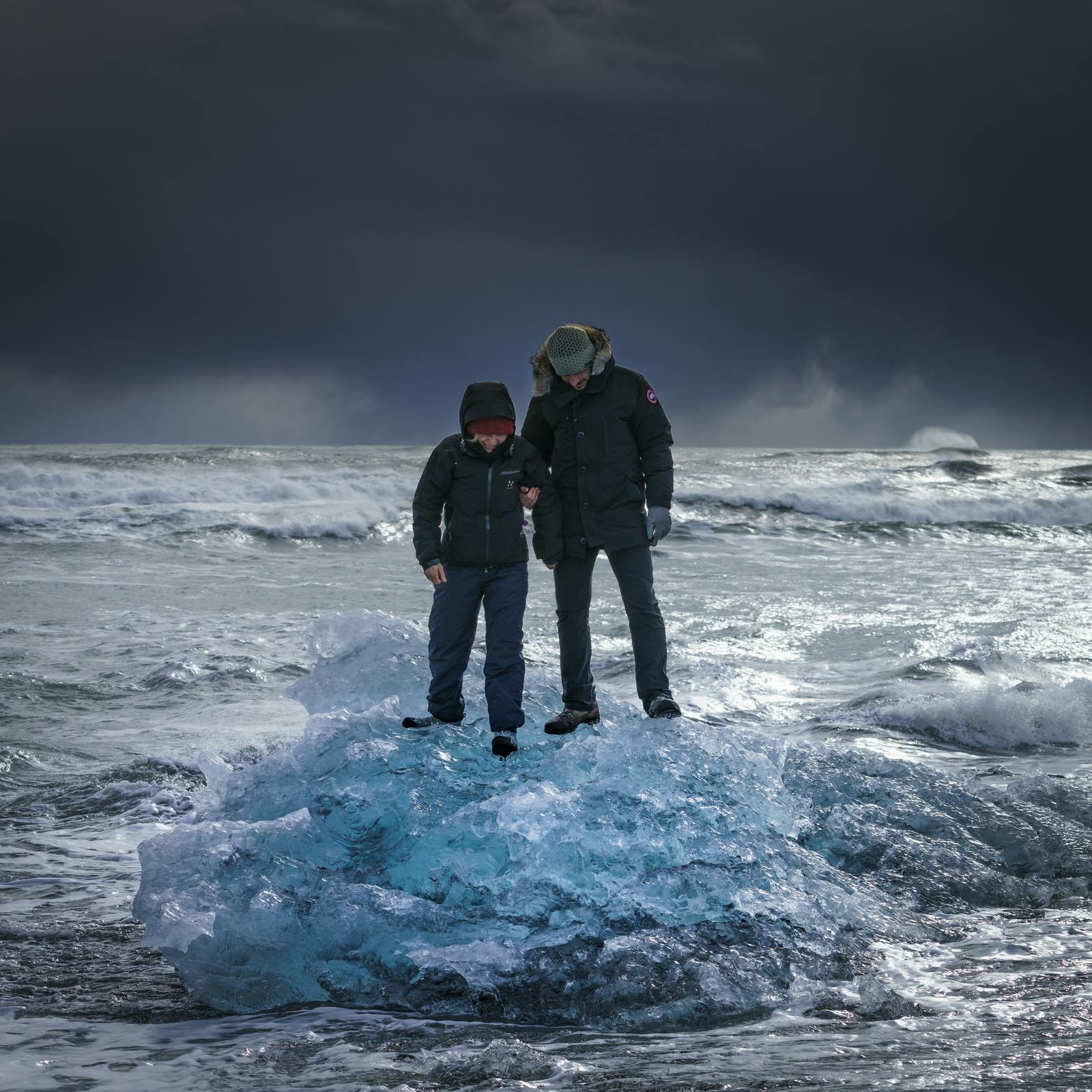 tourists standing on a small iceberg in on diamond beach