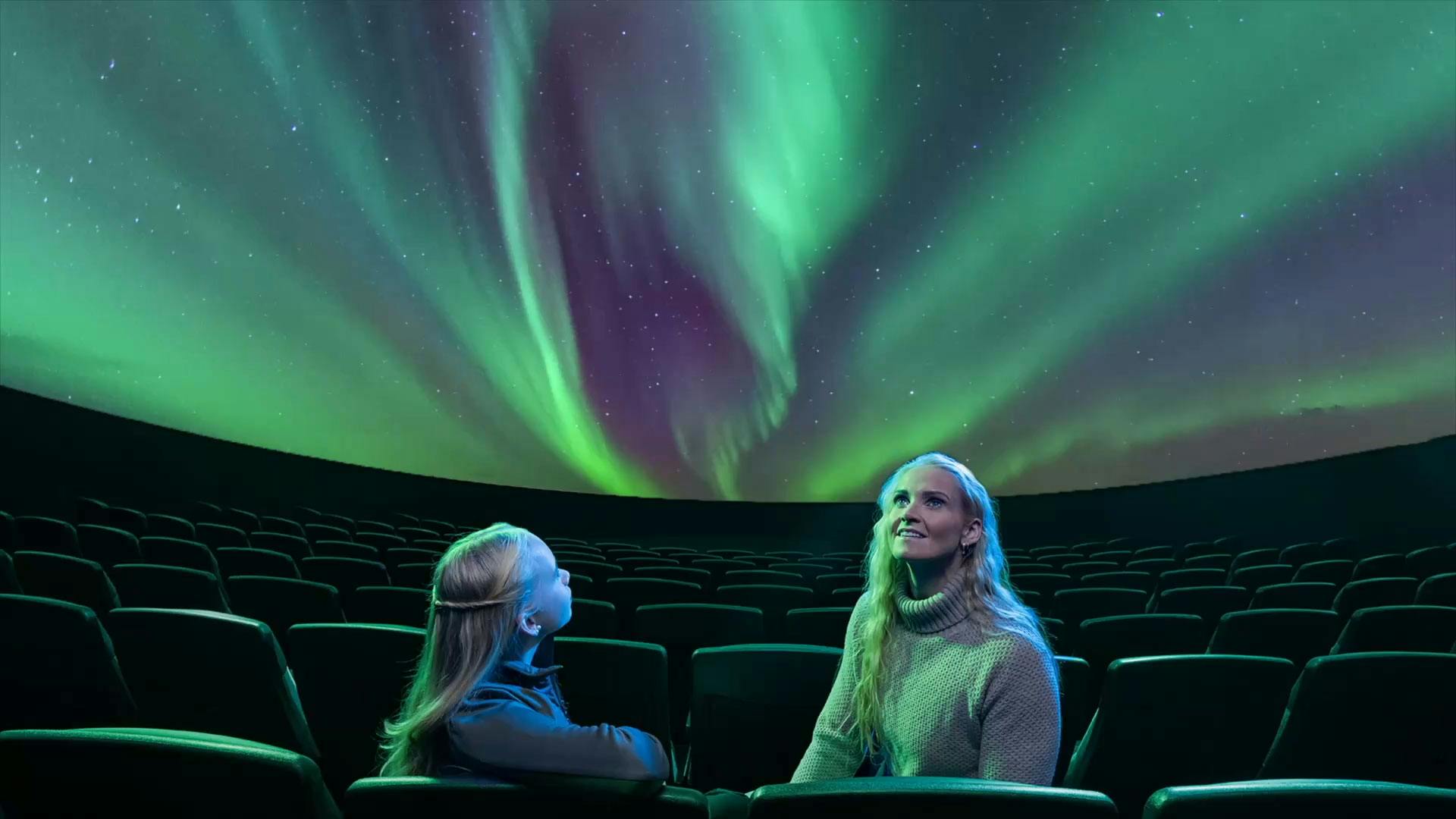 a mom and daughter watching the northern lights show in Reykjavík