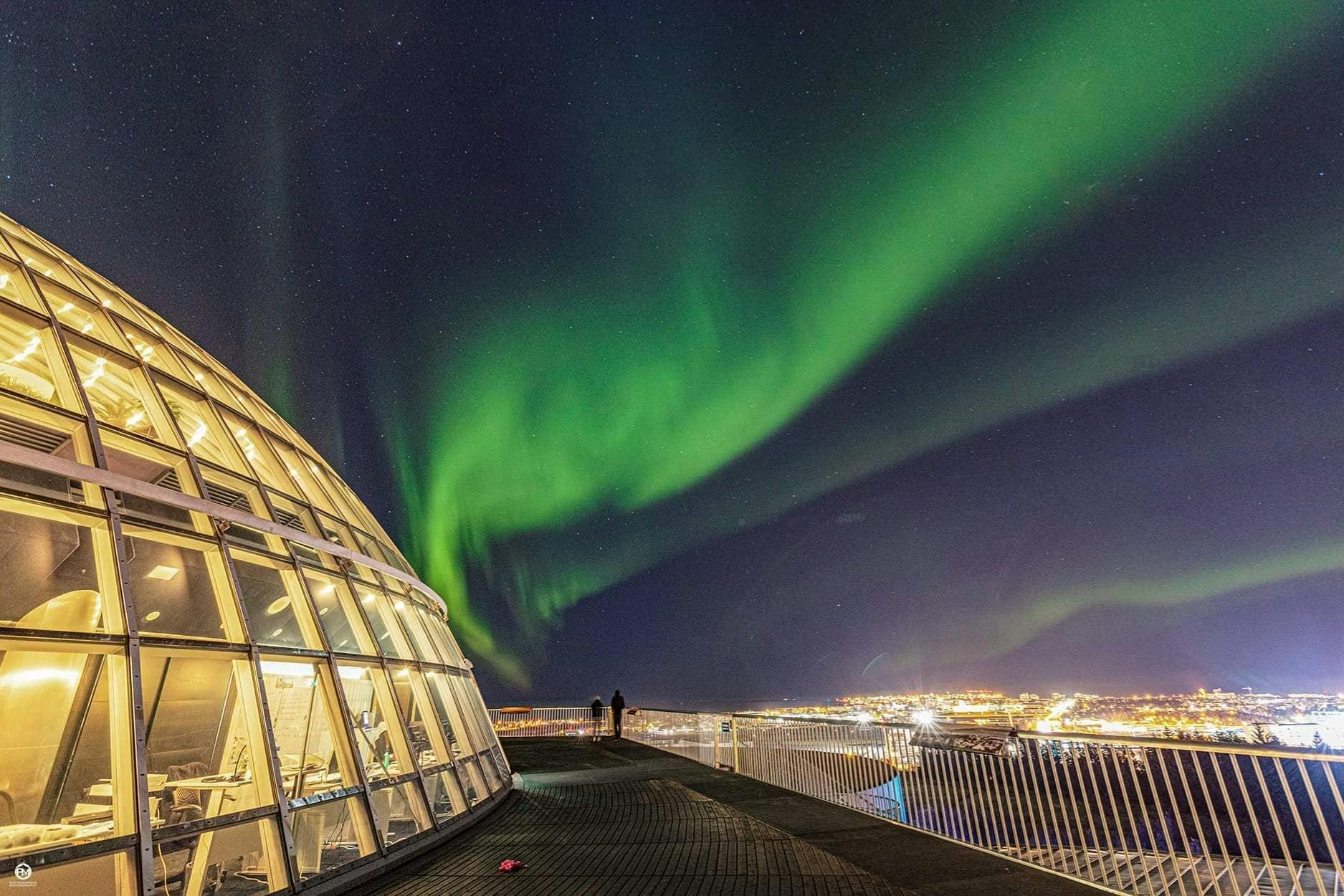 Green northern lights shown from perlans obervation deck over reykajvik