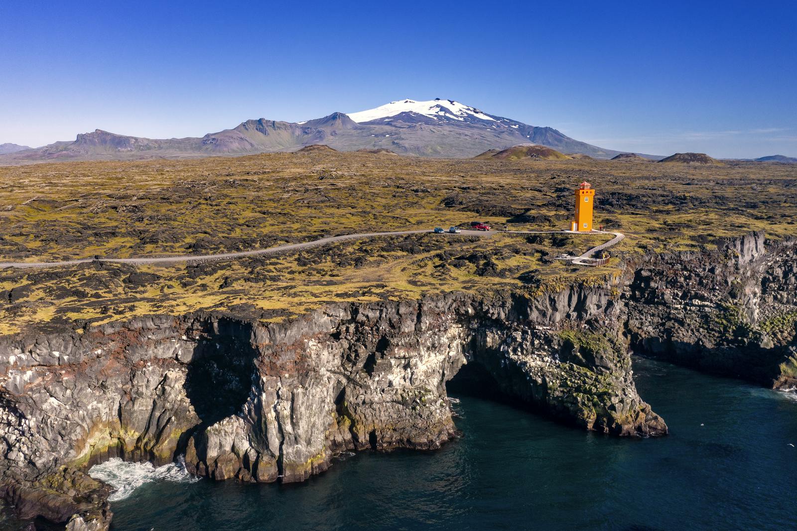 Orange lighthouse by Gerðuberg cliffs on a sunny day
