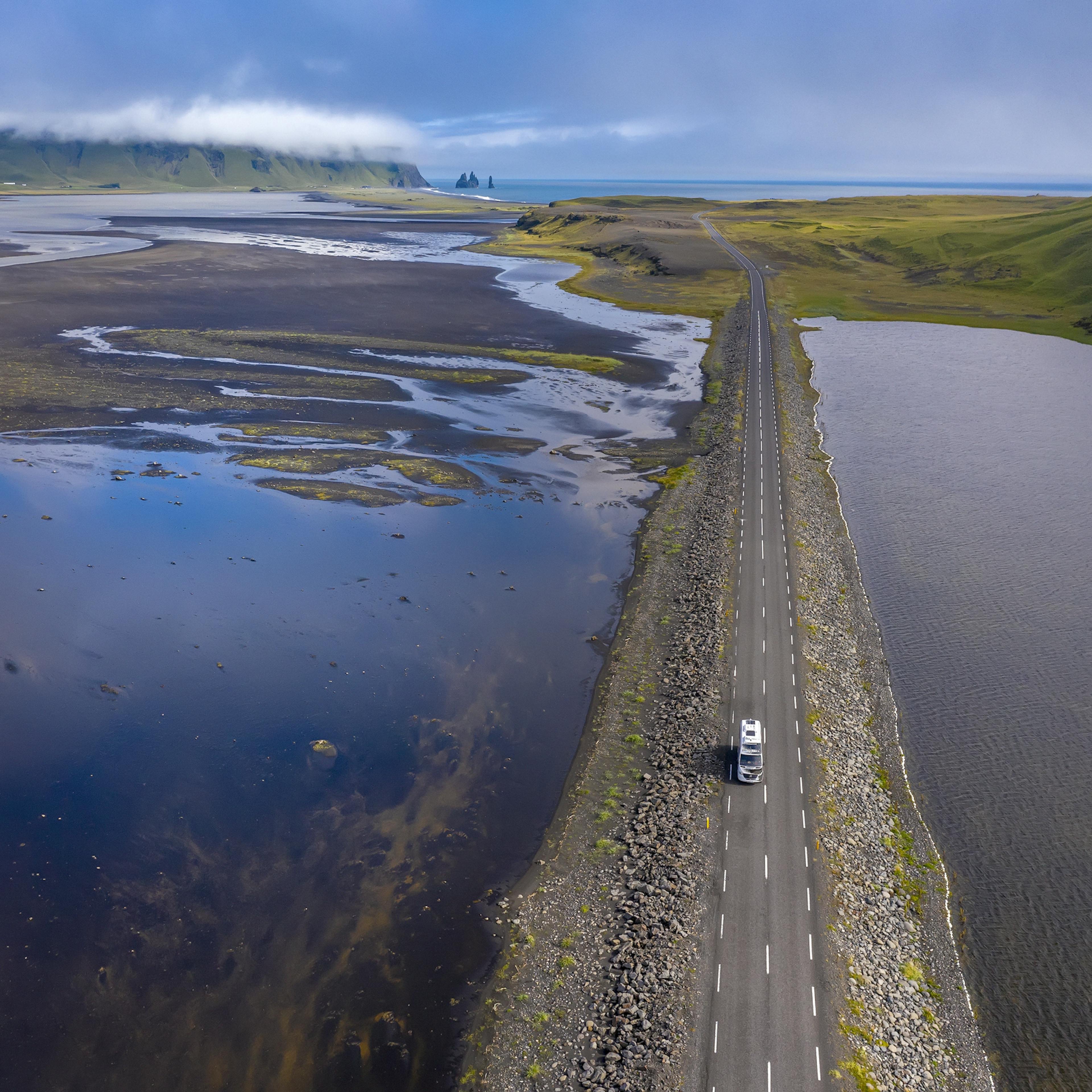 A car driving in the summer with Dyrhóley in the background
