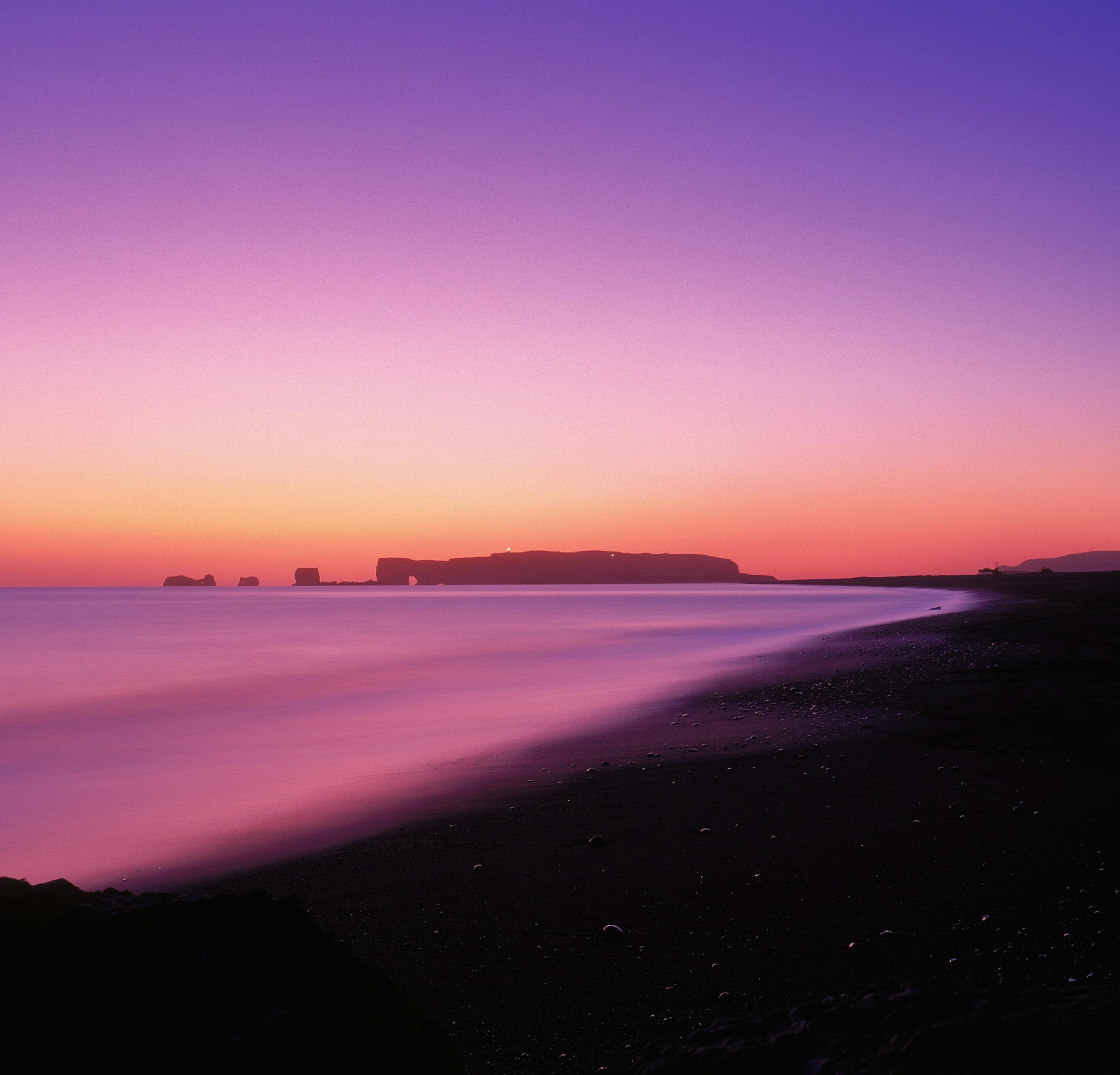 A full view of Dyrhóley and the lighthouse during sunset