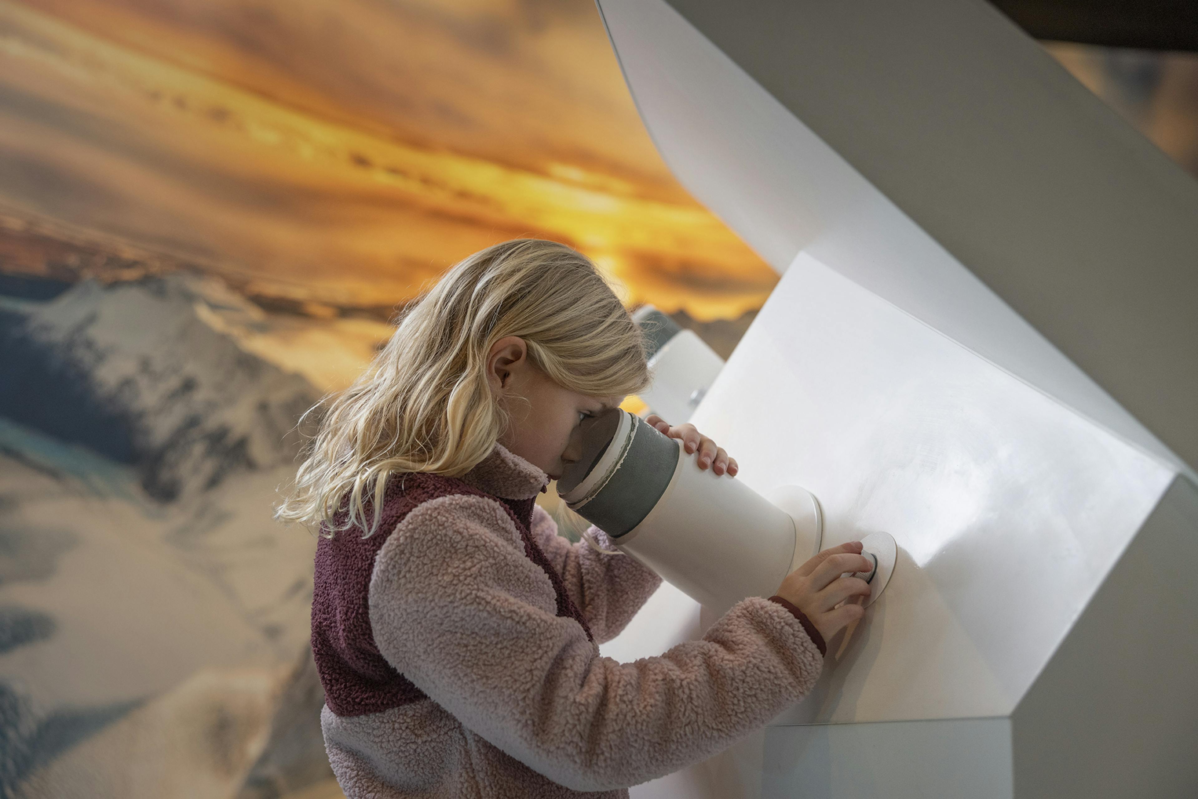 girl looking through a microscope in the glacier exhibit in reykjavik