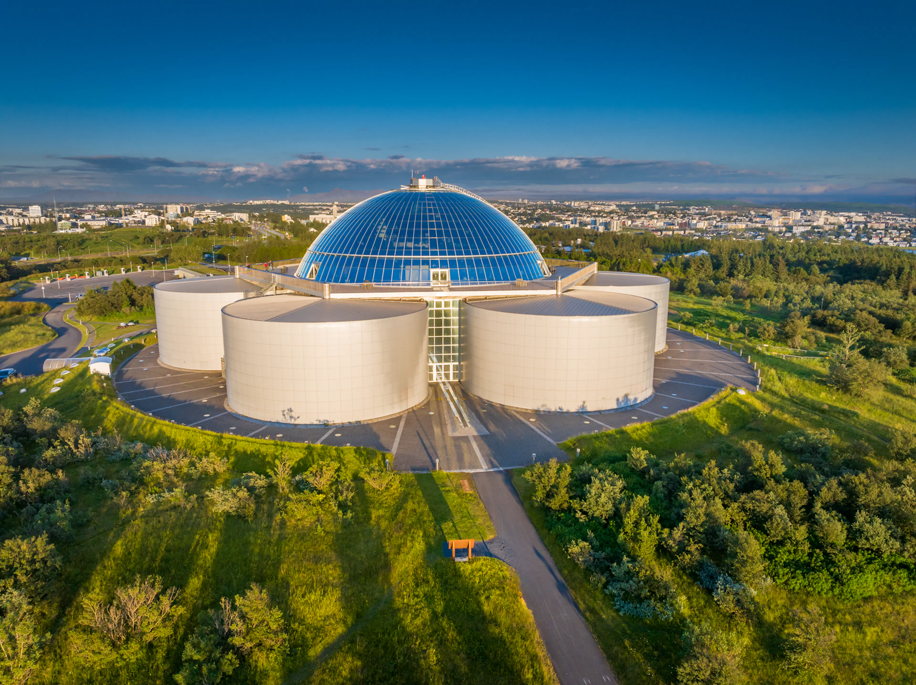 aerial view of Perlan in the summer with tiny people on the observation deck 
