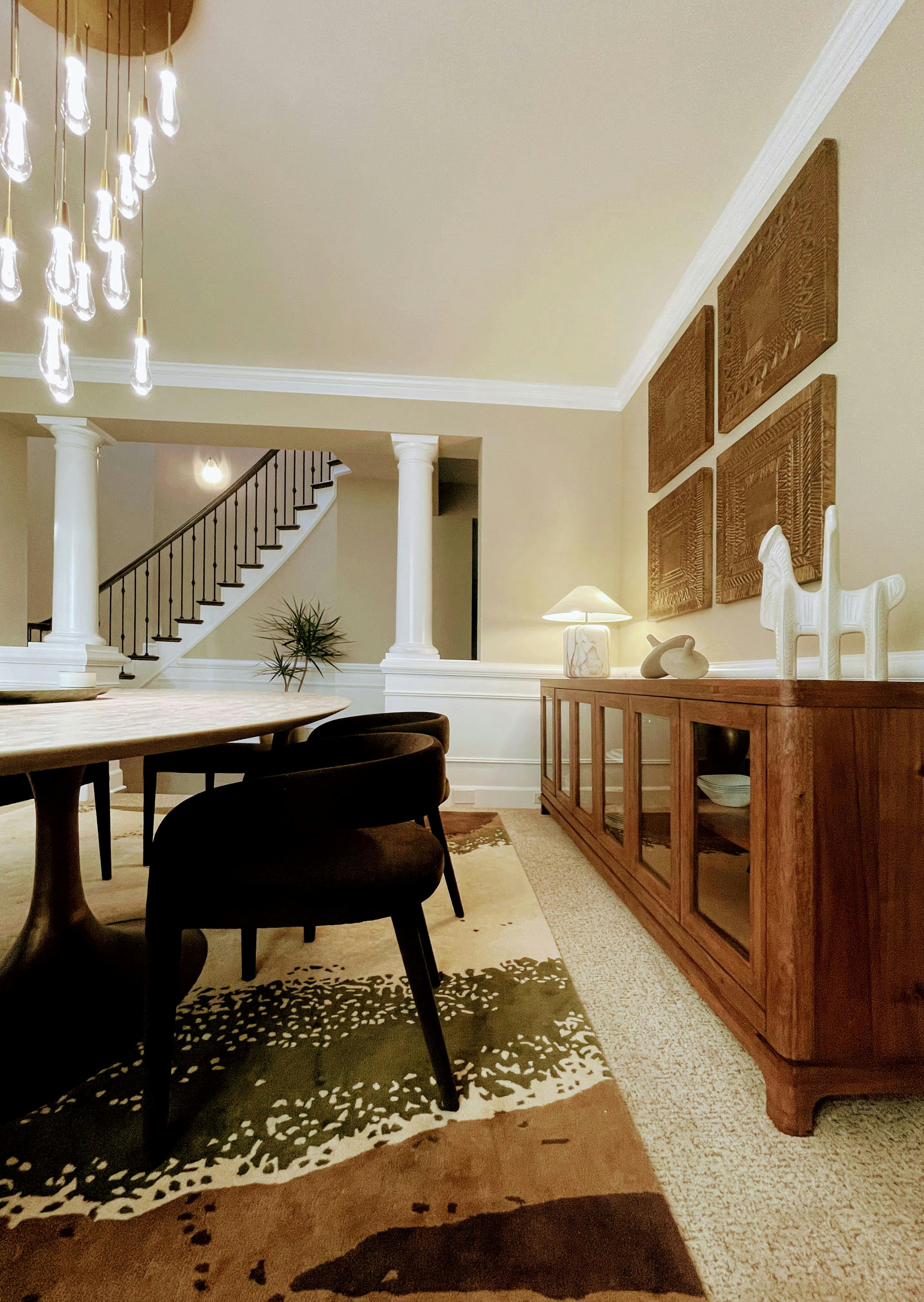 A bold rug with patterns of green and earthy tones sets the tone for this luxurious dining room designed by Persimmon Design