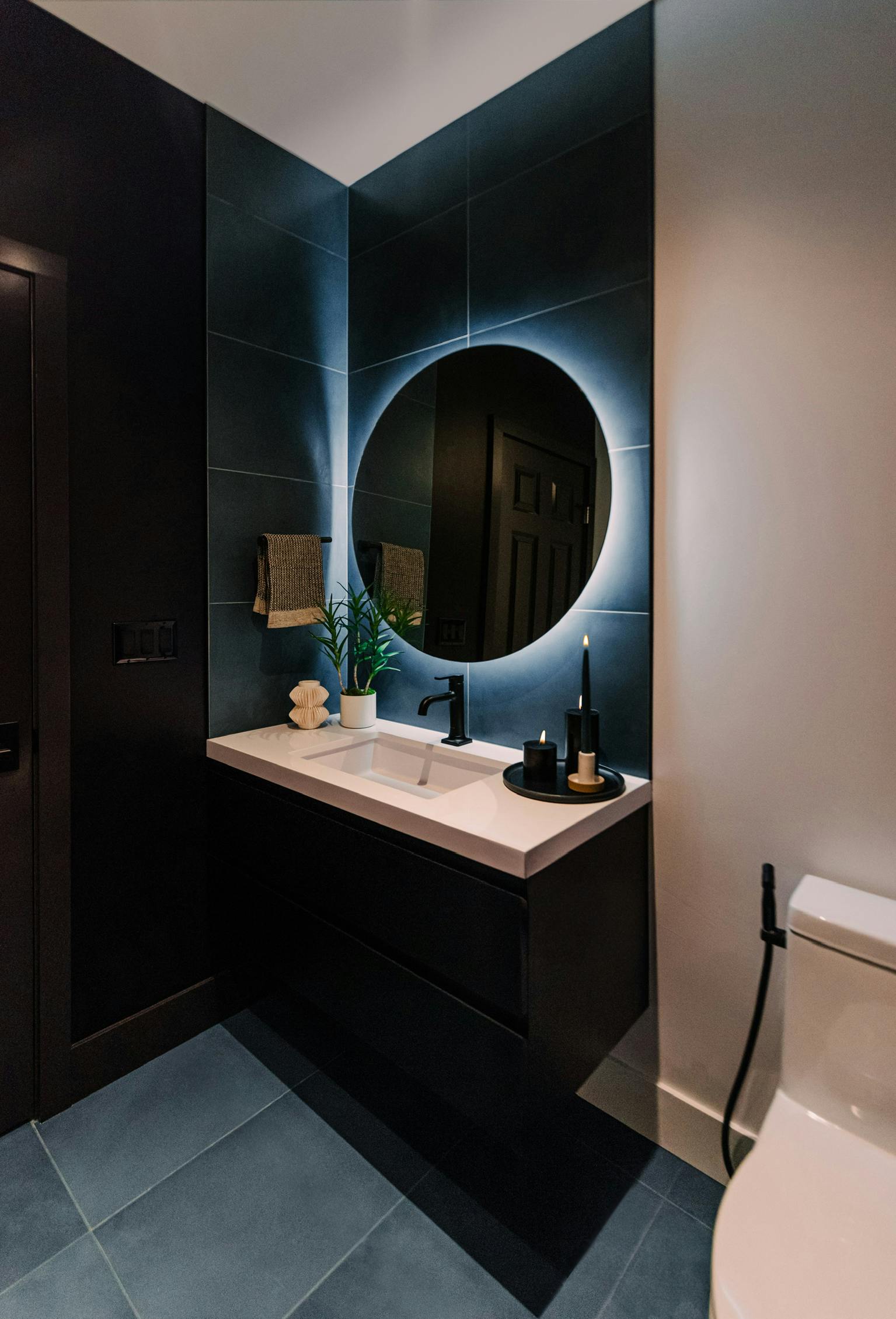 Black walls bookend crisp white surfaces and all are anchored in a sea of blue – Design by Persimmon Design