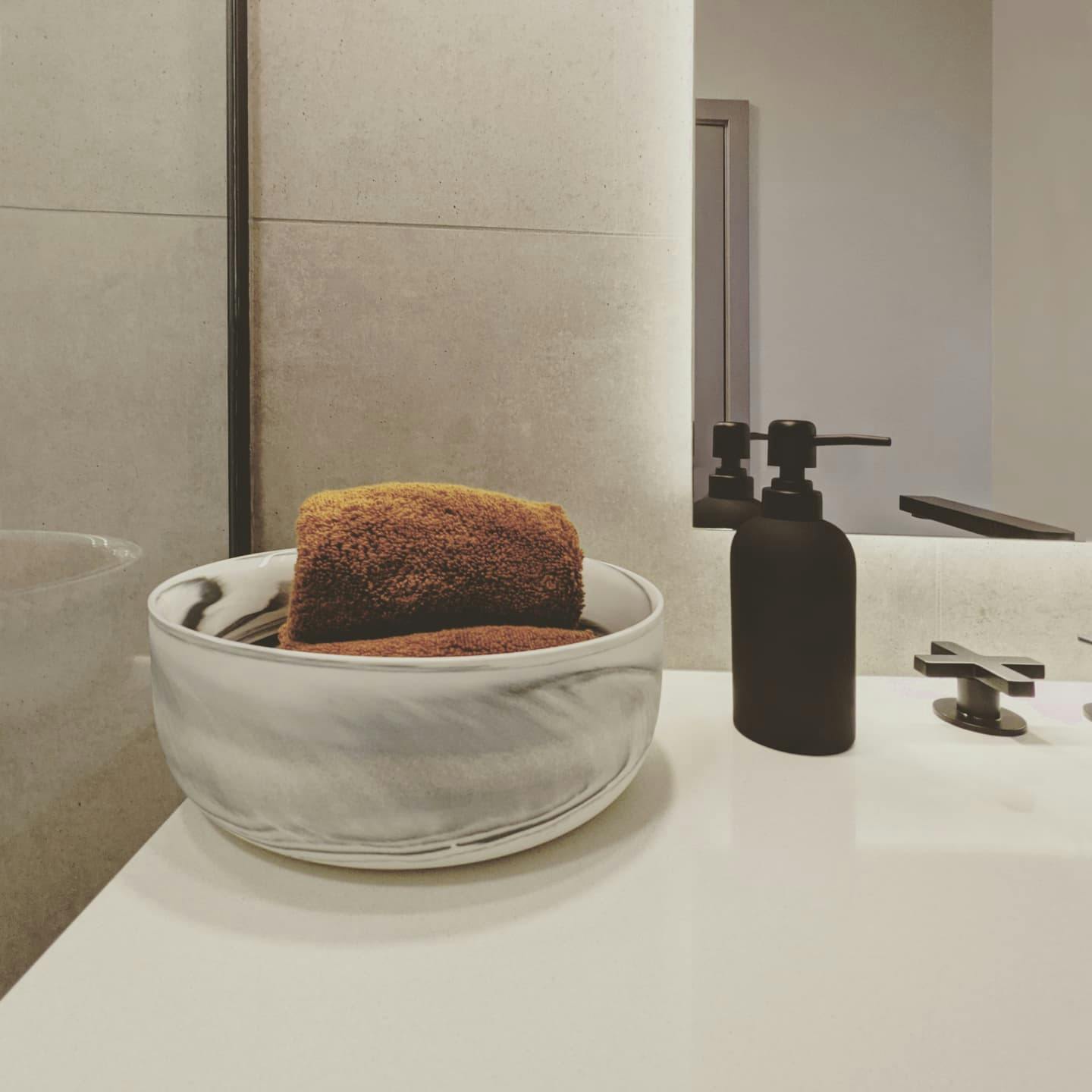 A motion-sensing backlit mirror and high-end plumbing fixtures lend a spa-like ambiance to this bathroom, thoughtfully designed by Persimmon Design.
