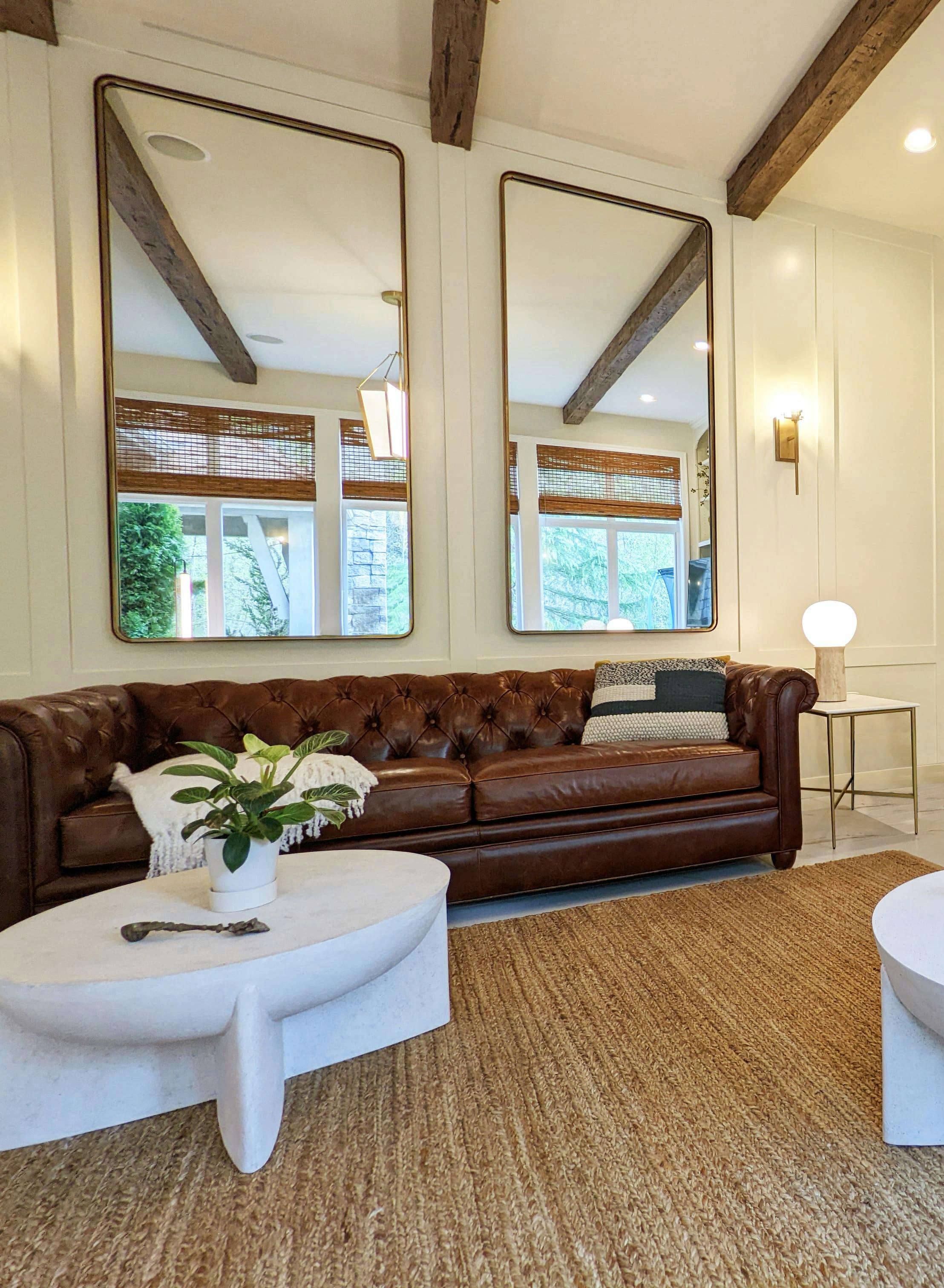 This resort-inspired living room by Persimmon Design captures the spirit of an relaxing escape. Graceful, oversized mirrors pull the greenery inside, blurring the boundary between home and nature, while warm textures and a rich leather sofa ground the space in comfort.
