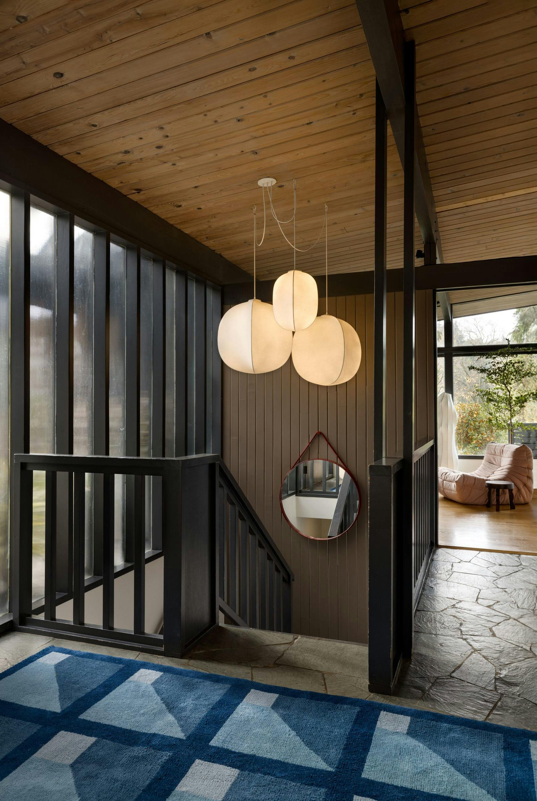 This entryway by Persimmon Design is striking on its own, yet a blush Fireside Togo chair by Ligne Roset gently guides the eye toward the warm glow of the family room.