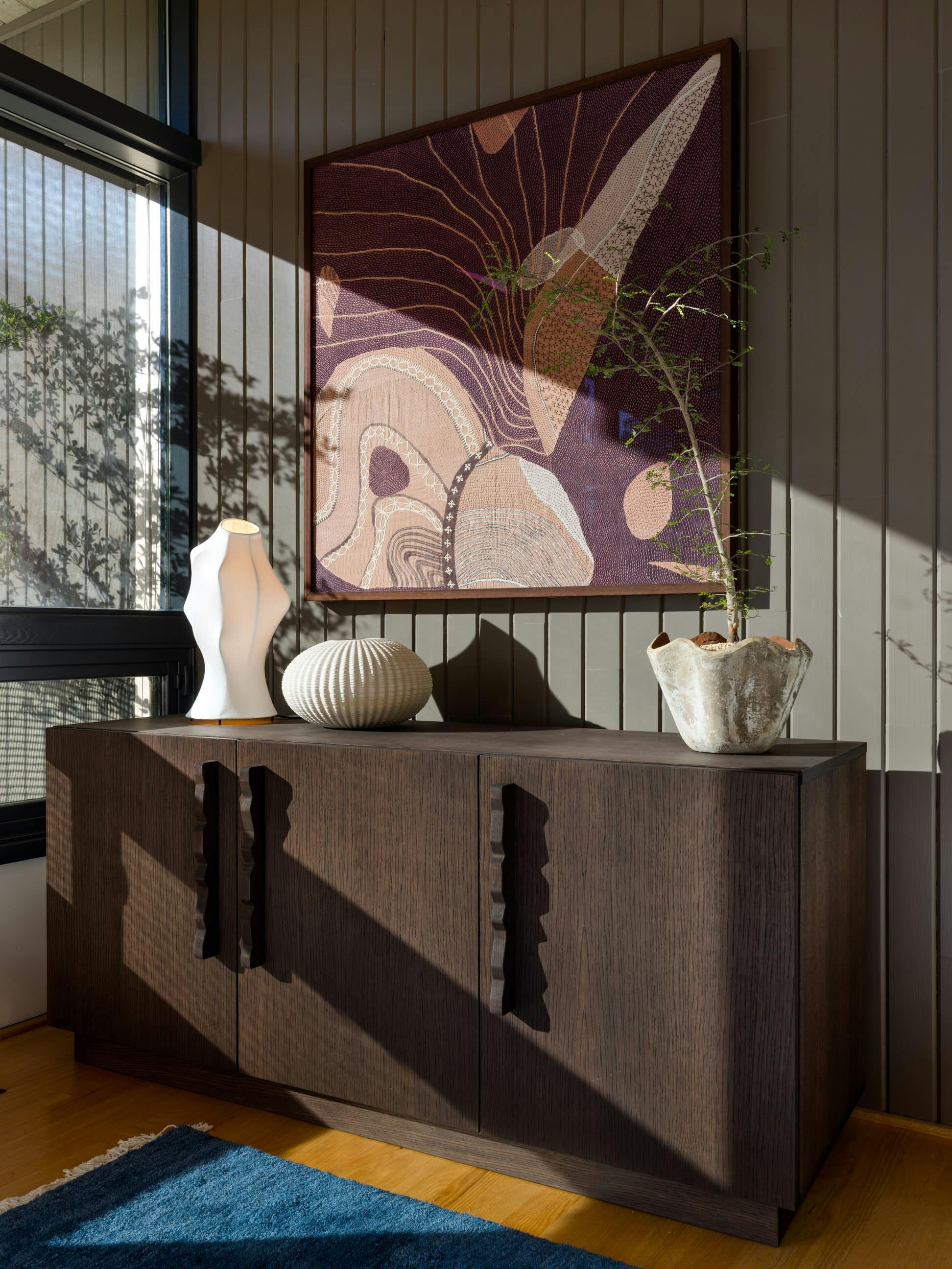 Craftsmanship leads the conversation in this nook by Persimmon Design: a meticulously woven tapestry, a beautifully detailed wood sideboard, and an amorphous lamp that softens the composition.  Photo courtesy: Miranda Estes Photography