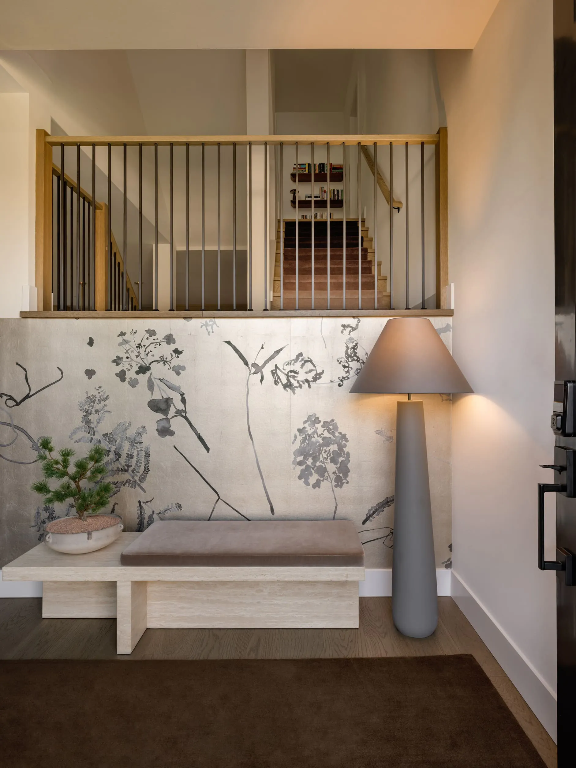 In this entry foyer by Persimmon Design, the large floor lamp washes the botanical wallcovering and travertine bench in amber tones that bring out exactly the depth and softness those materials were chosen for. Without it, the wallcovering would flatten, and the stone would go cool and inert, and the whole entry would feel uninspiring.