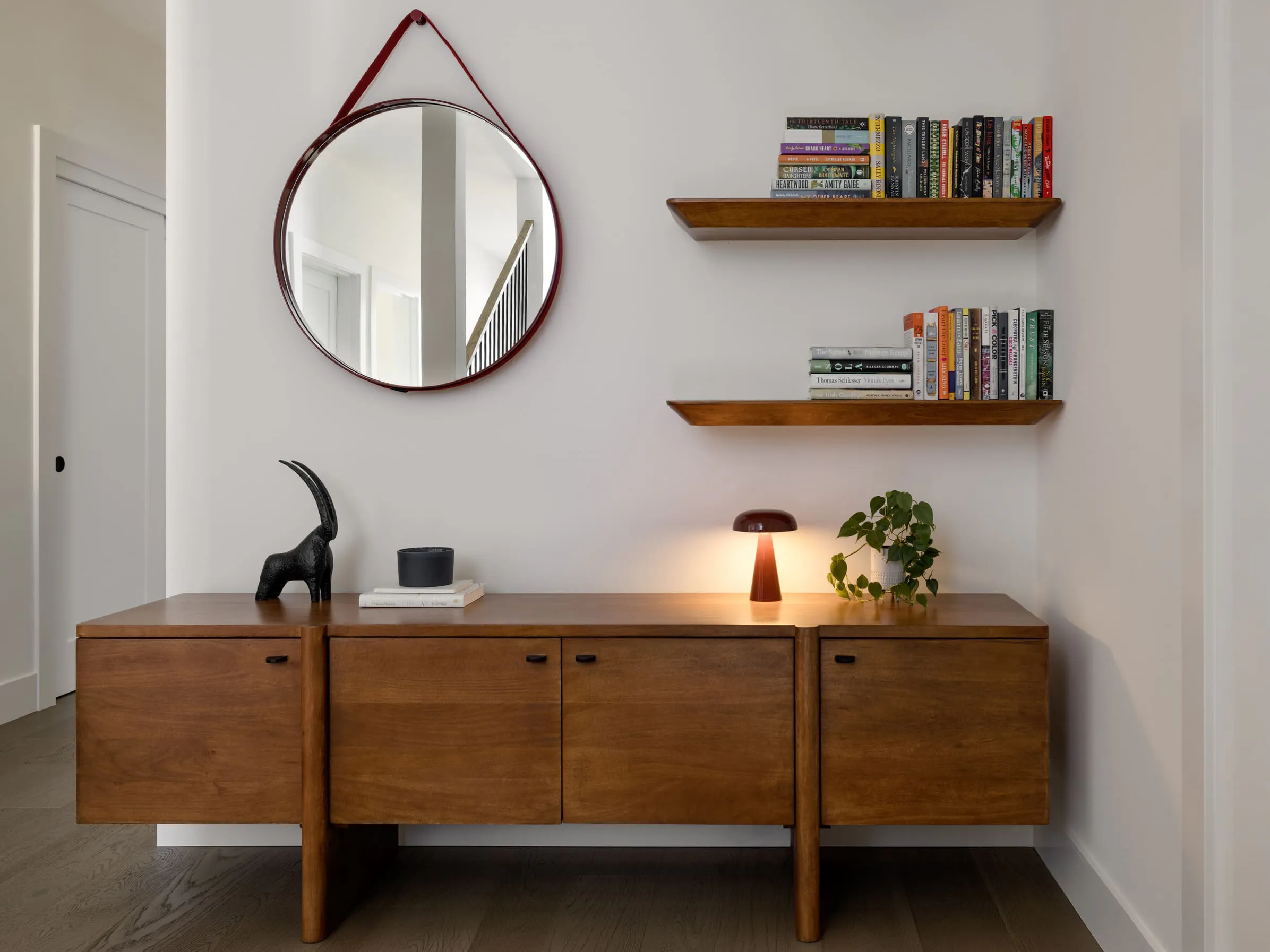 This mini home library by Persimmon Design transforms the top of a stair landing into a warm, personality-filled moment with rich wood tones and thoughtful styling. Photography credit: Miranda Estes Photography