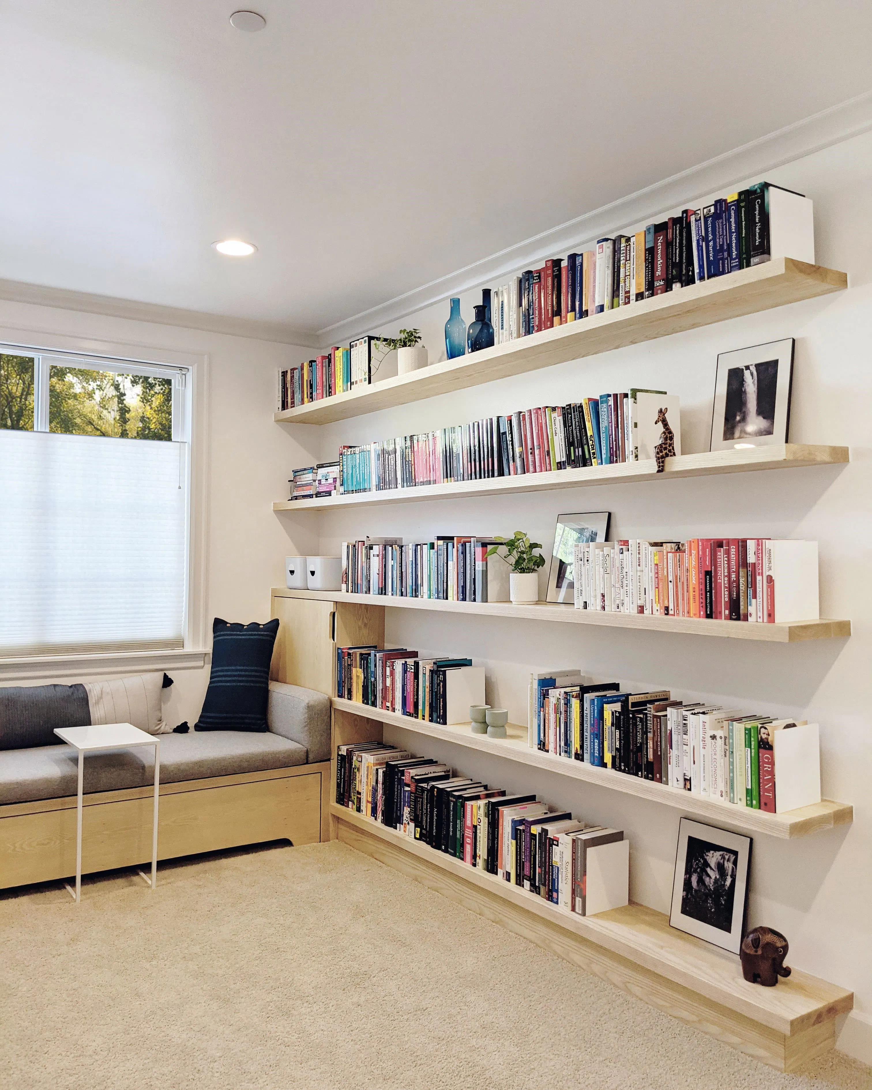 A quiet corner for slow reading and everyday retreat designed by Persimmon Design. This light-filled home library pairs floating oak shelves with a custom built-in window seat to create a space that feels both calm and tailored.