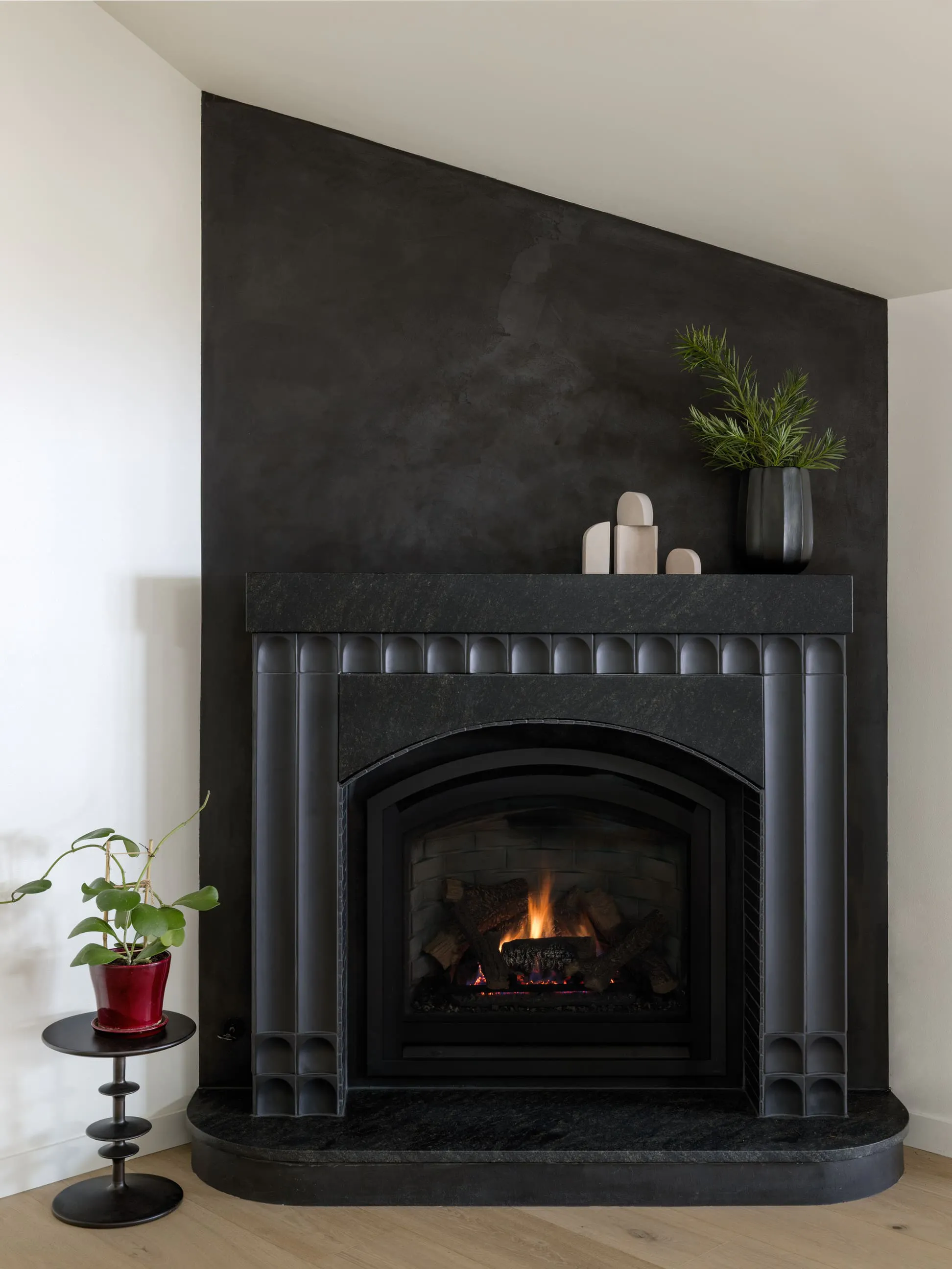 The three-dimensional arched tiles of this custom fireplace by Persimmon Design lead the composition, establishing rhythm and depth, while surrounding elements remain restrained, creating clarity through contrast. 