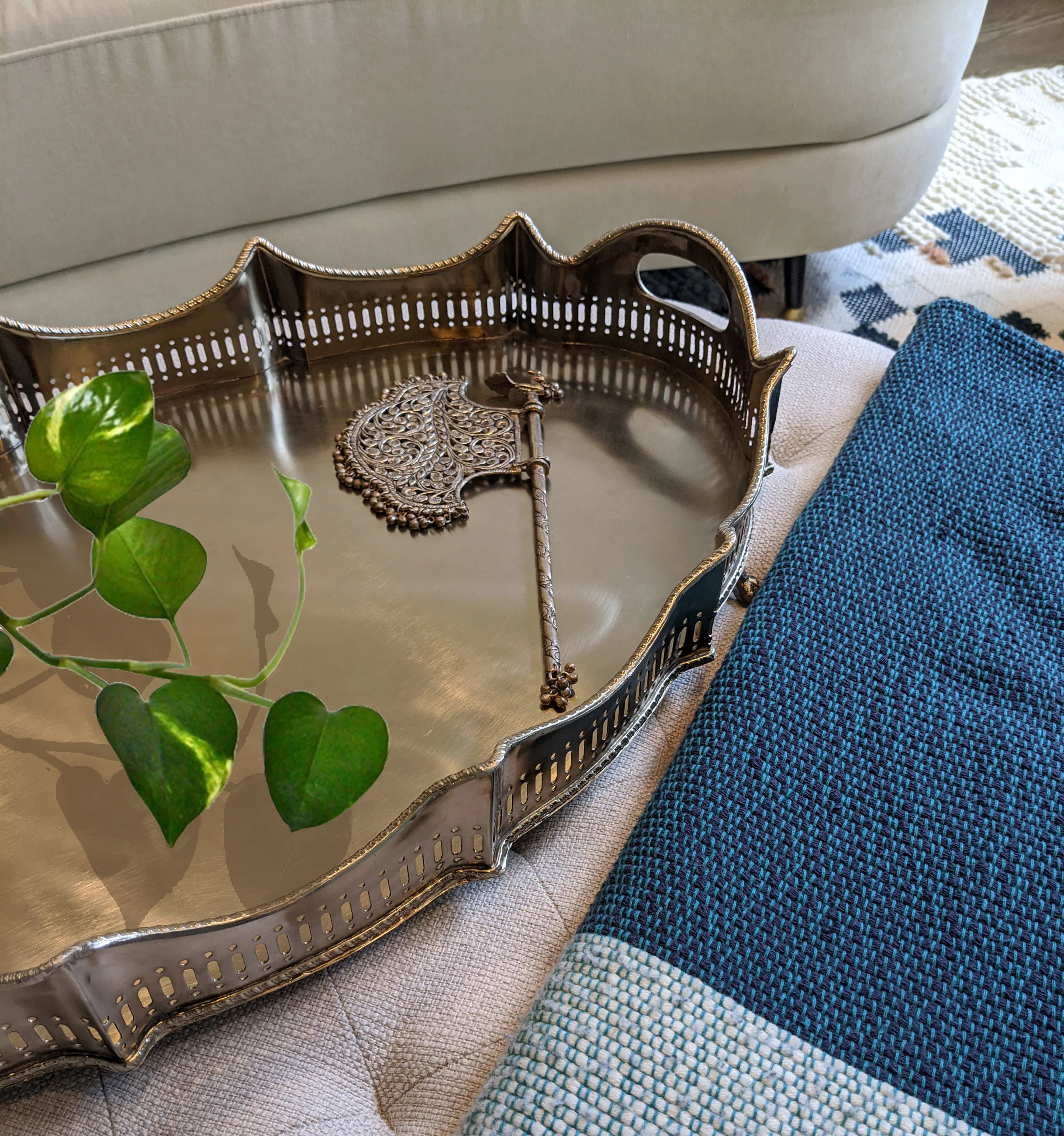 The gentle sheen of the metal tray catches light without overwhelming the composition of this living room by Persimmon Design, demonstrating how polished accents can introduce brightness and refinement within a palette of softer, tactile materials. 